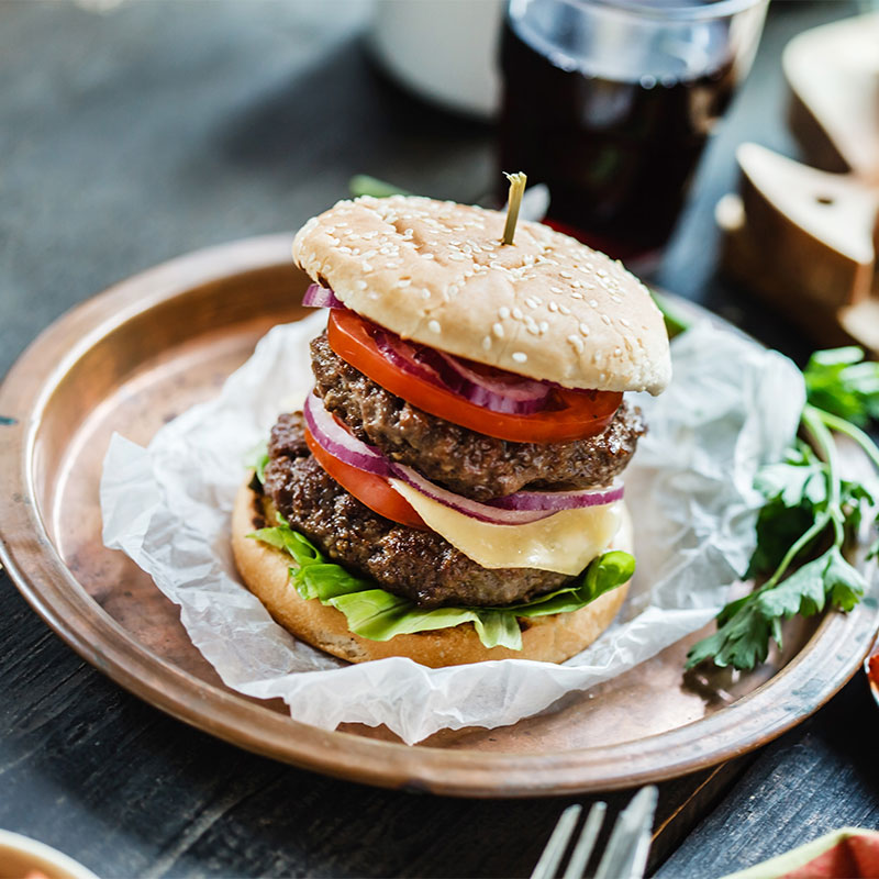 A cheeseburger on a copper tray