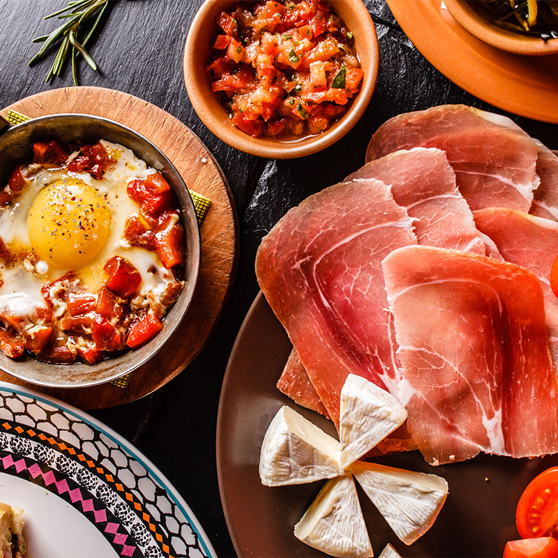 Shakshuka beside sliced ham and tomatoes