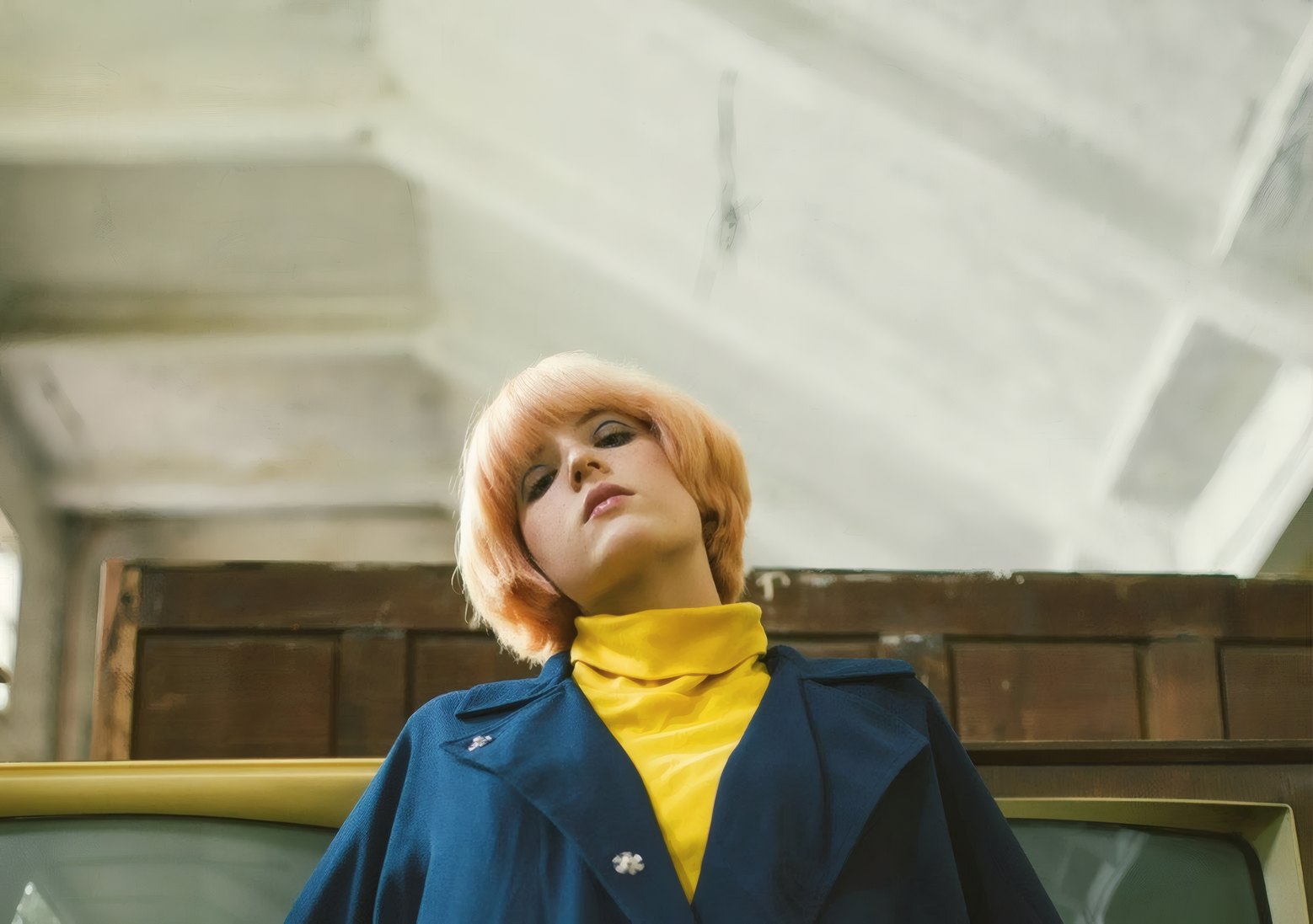 A woman in a navy wool swing coat over a mustard roll-neck