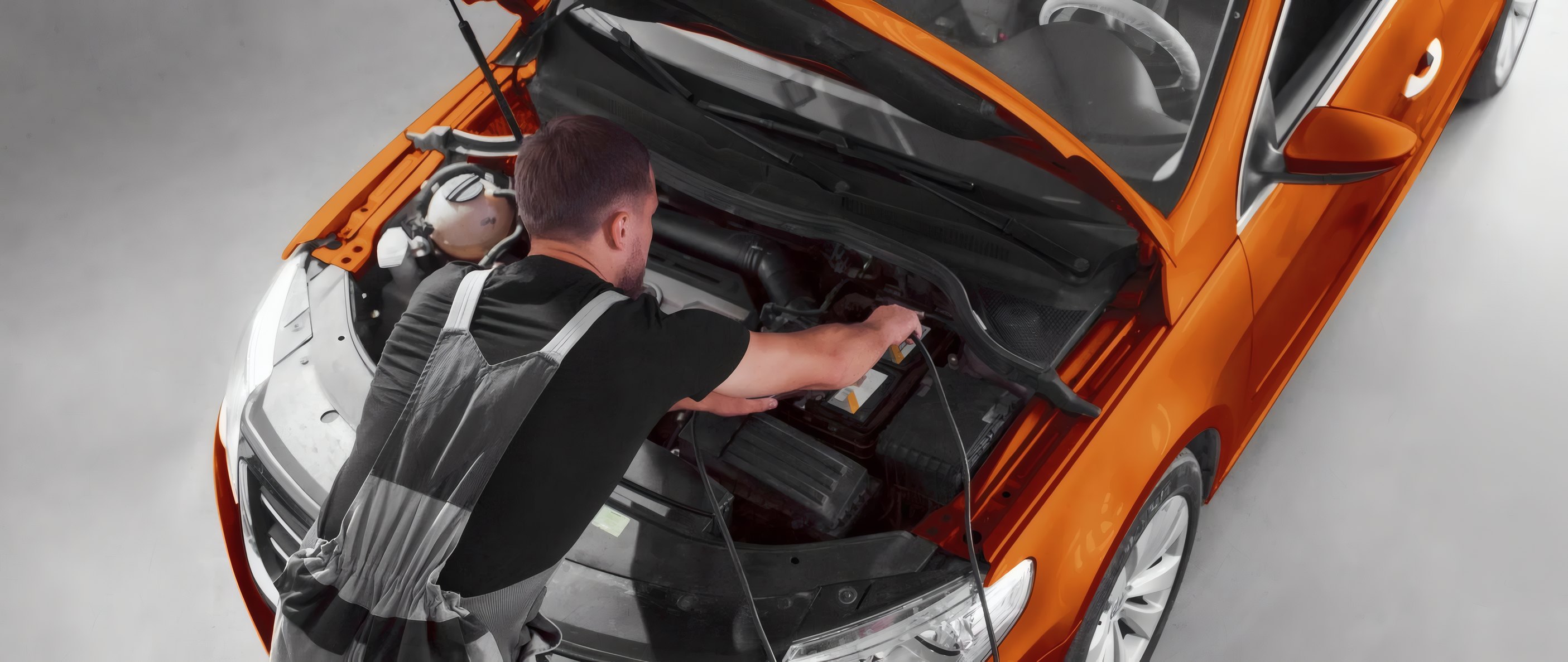 A technician under the bonnet of an orange car