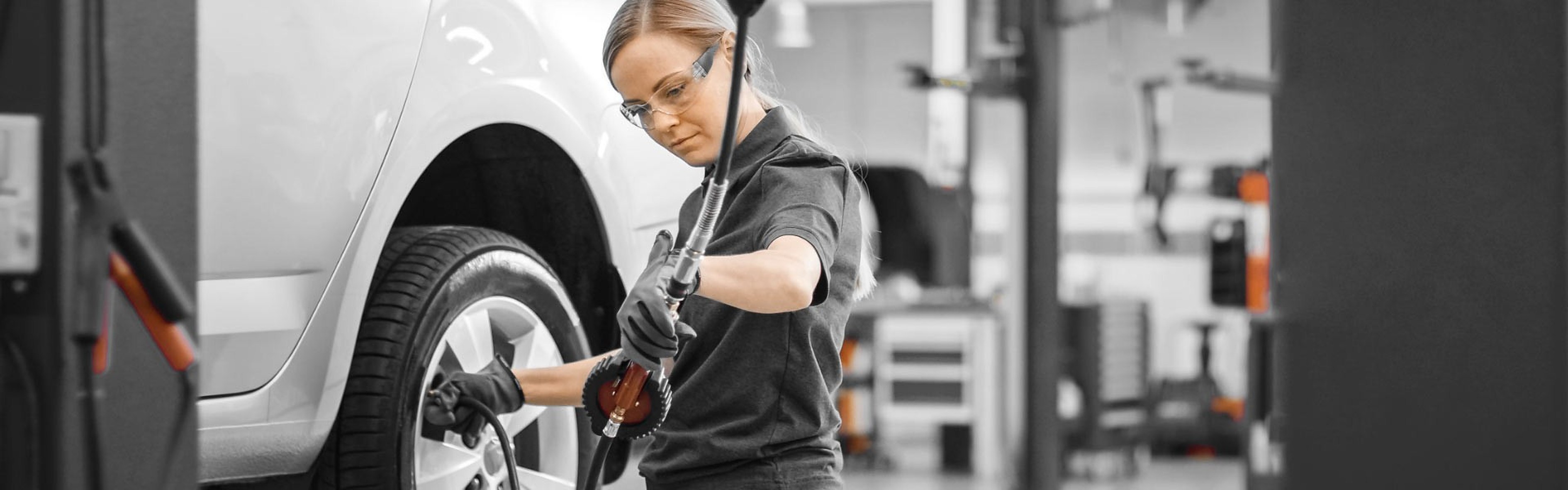 A technician at the wheel of a white car in a light workshop
