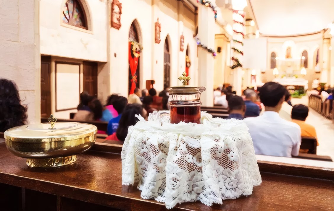 Candles and a lace-covered bowl in a full church