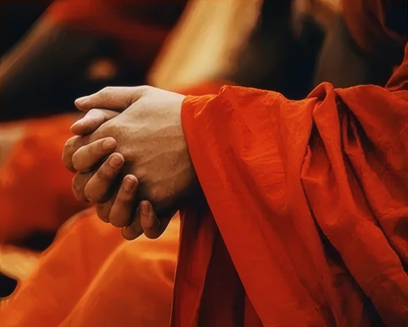 Hands folded over saffron robes