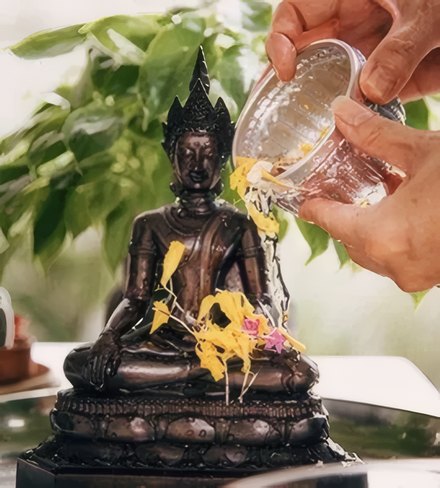 Water poured over a small Buddha