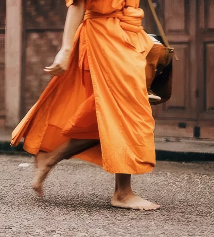 A monk walking barefoot in saffron robes