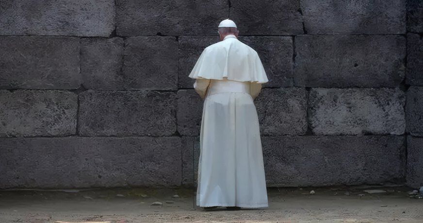A priest praying at a stone wall