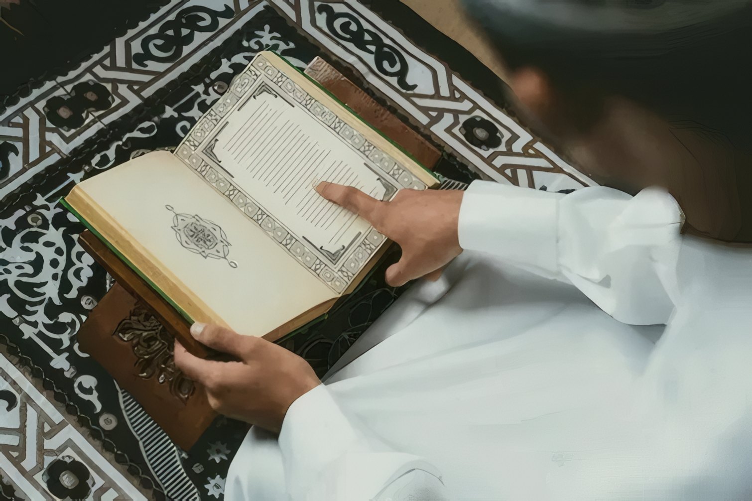 A student reading the Quran on a prayer rug