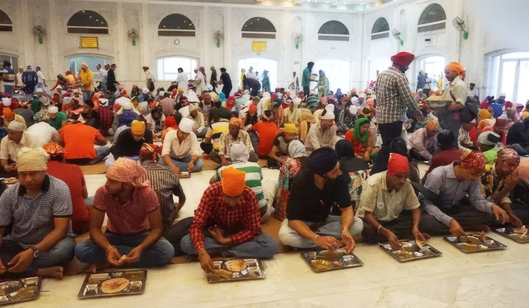 The sangat seated in rows for langar