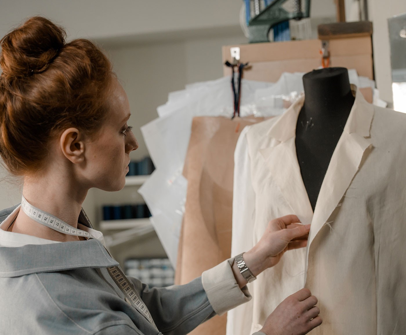 A tailor working on a jacket on the dress form