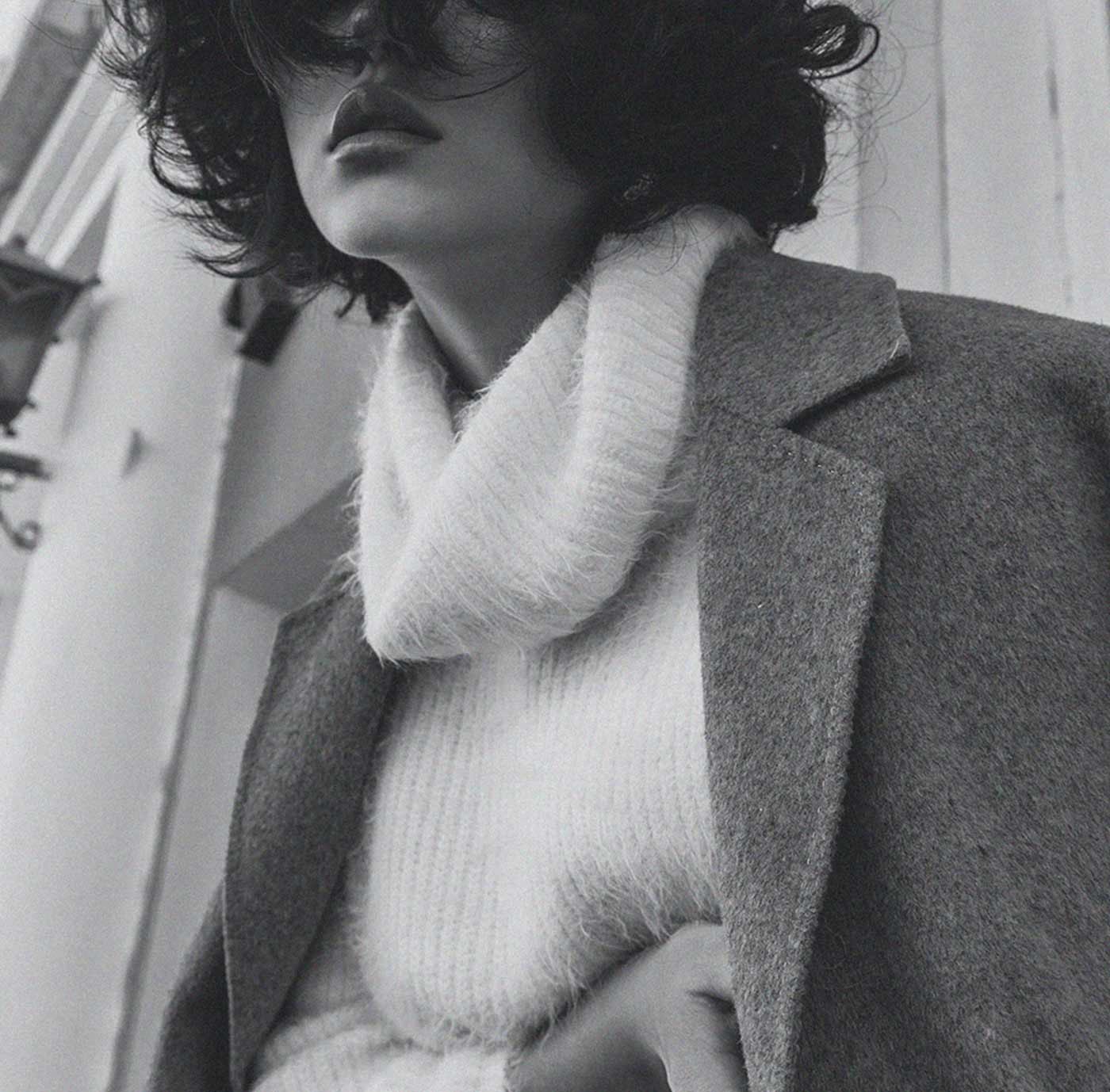 A woman in a grey coat and a fluffy white scarf