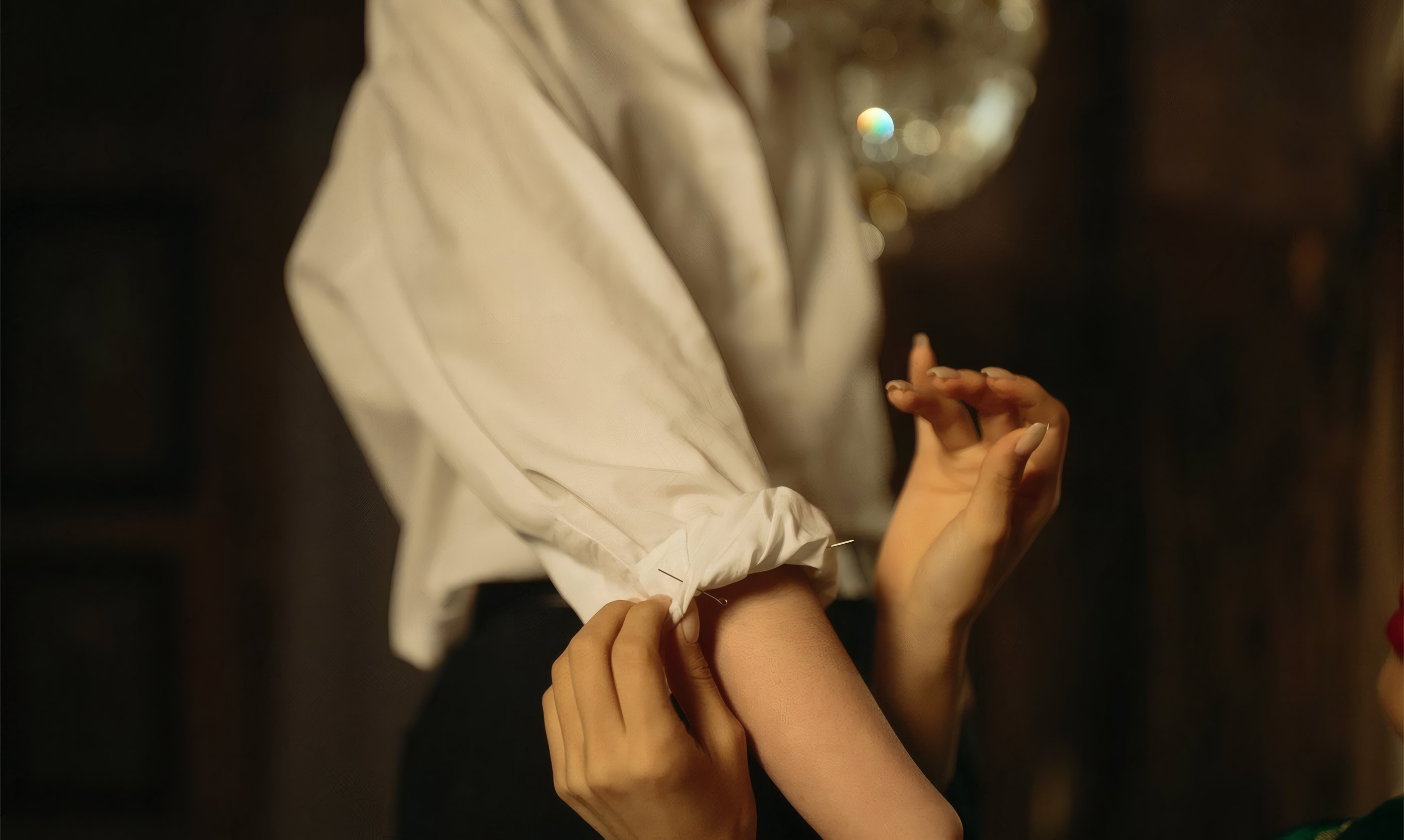 A tailor fastening a shirt cuff
