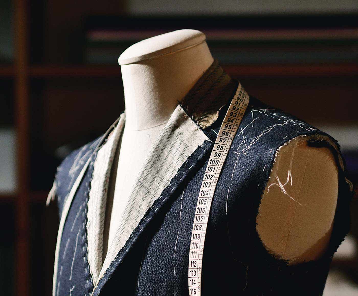 A waistcoat basted on a dress form with a tape measure