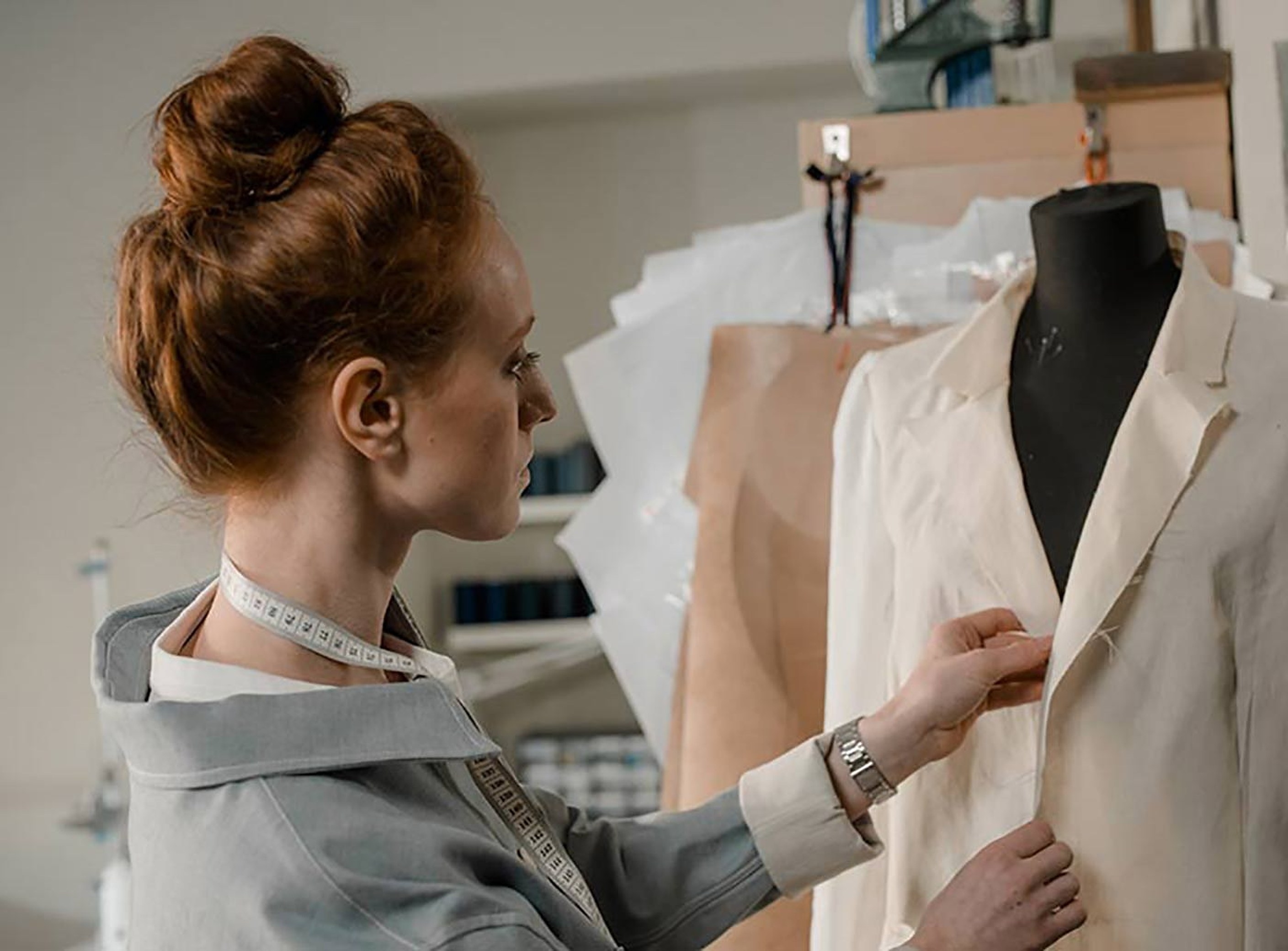 A tailor fitting a jacket on a dress form