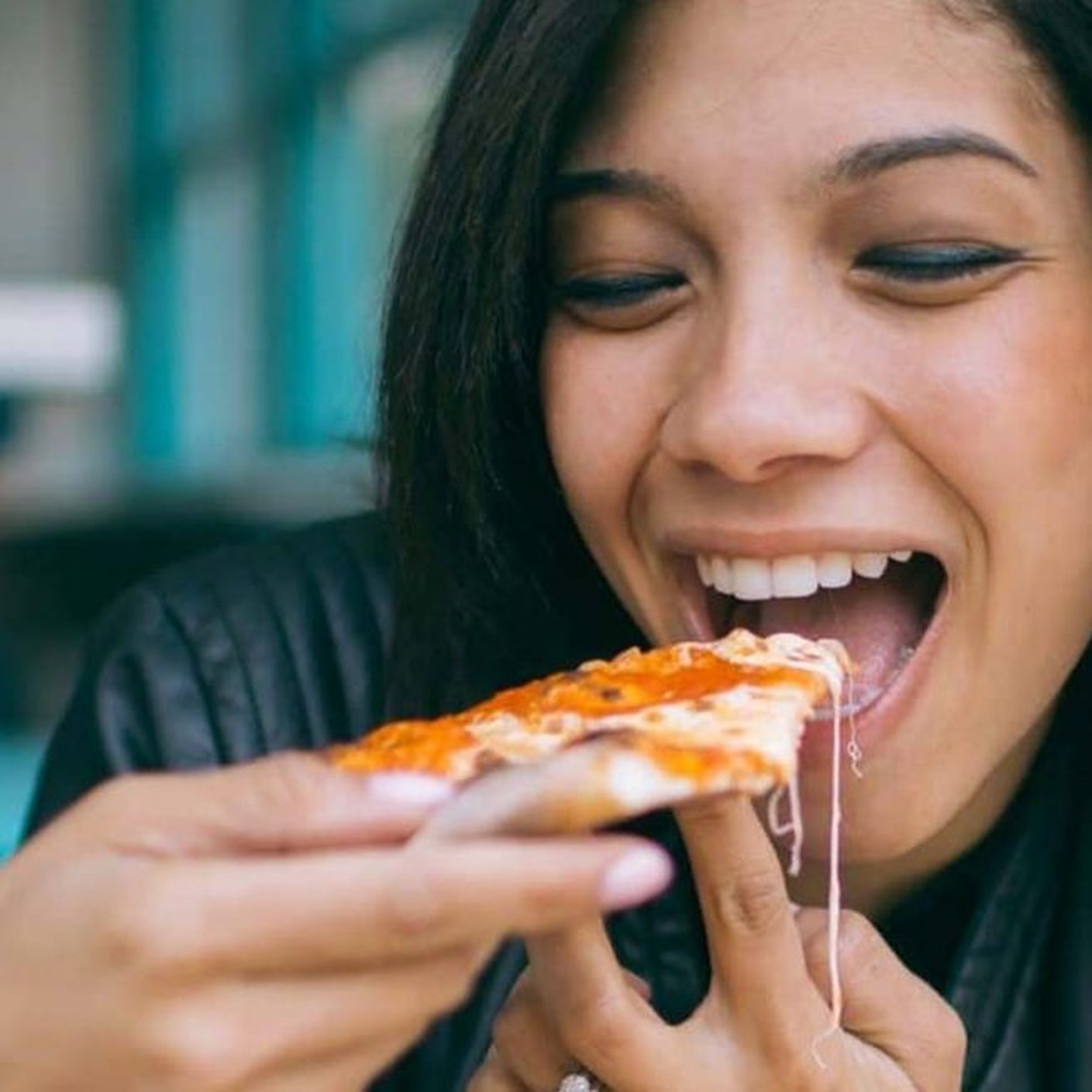 A woman pulling a cheesy slice