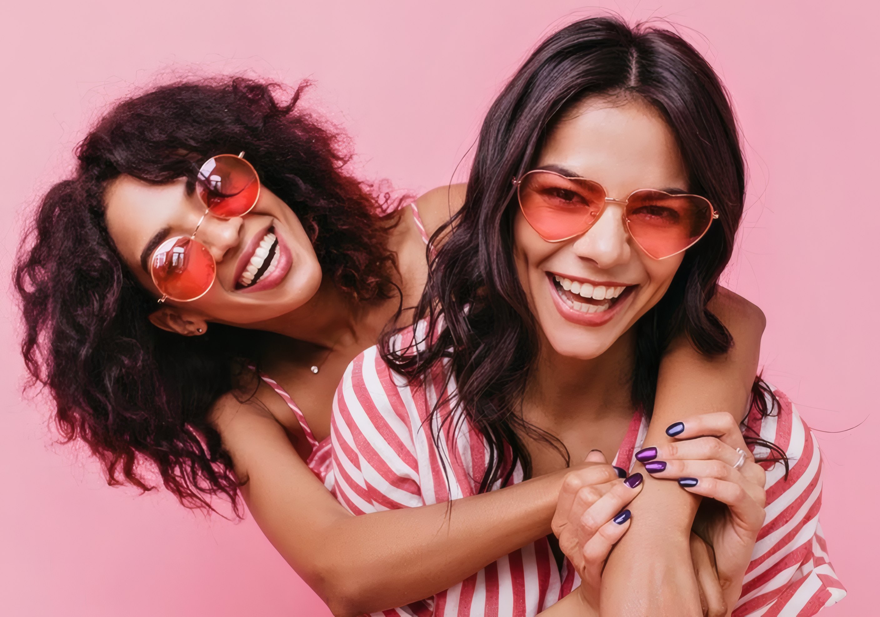 Two friends laughing in red heart-shaped sunglasses