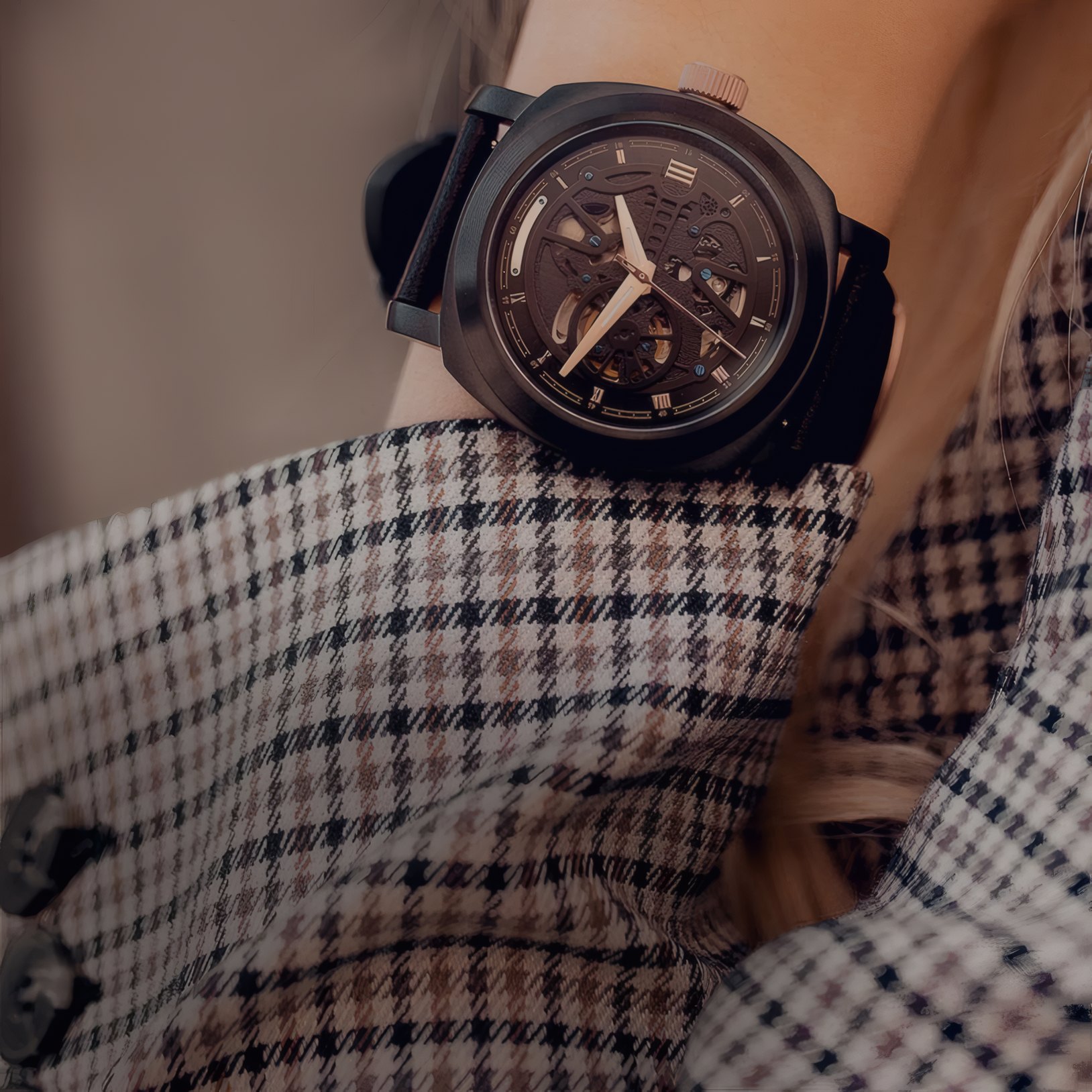 A black chronograph on a wrist against a tweed coat