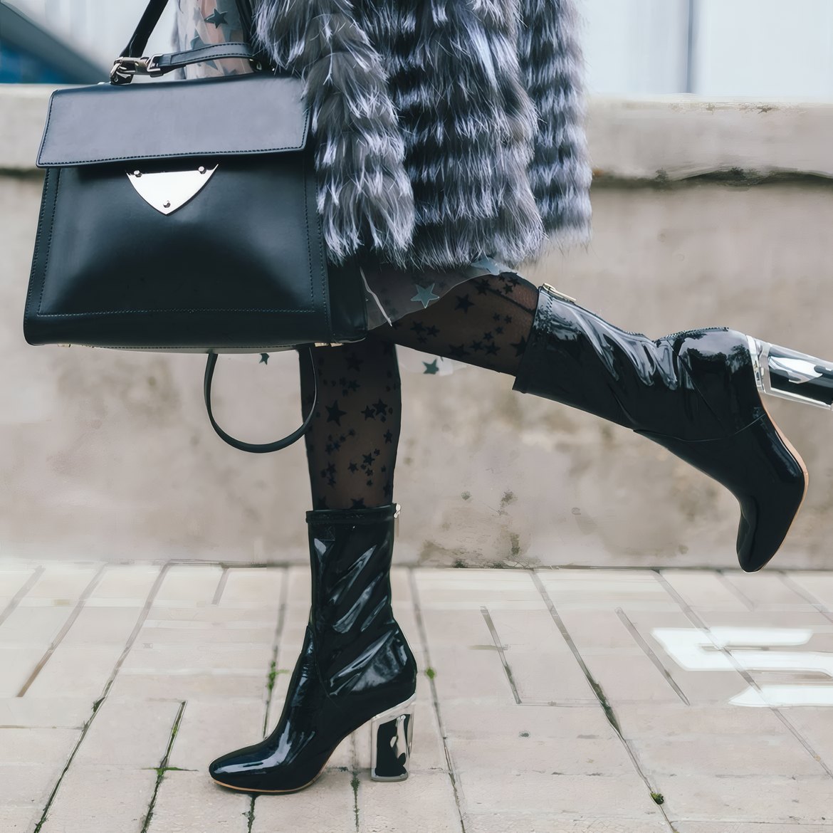 Black heeled boots and a black handbag on a city pavement