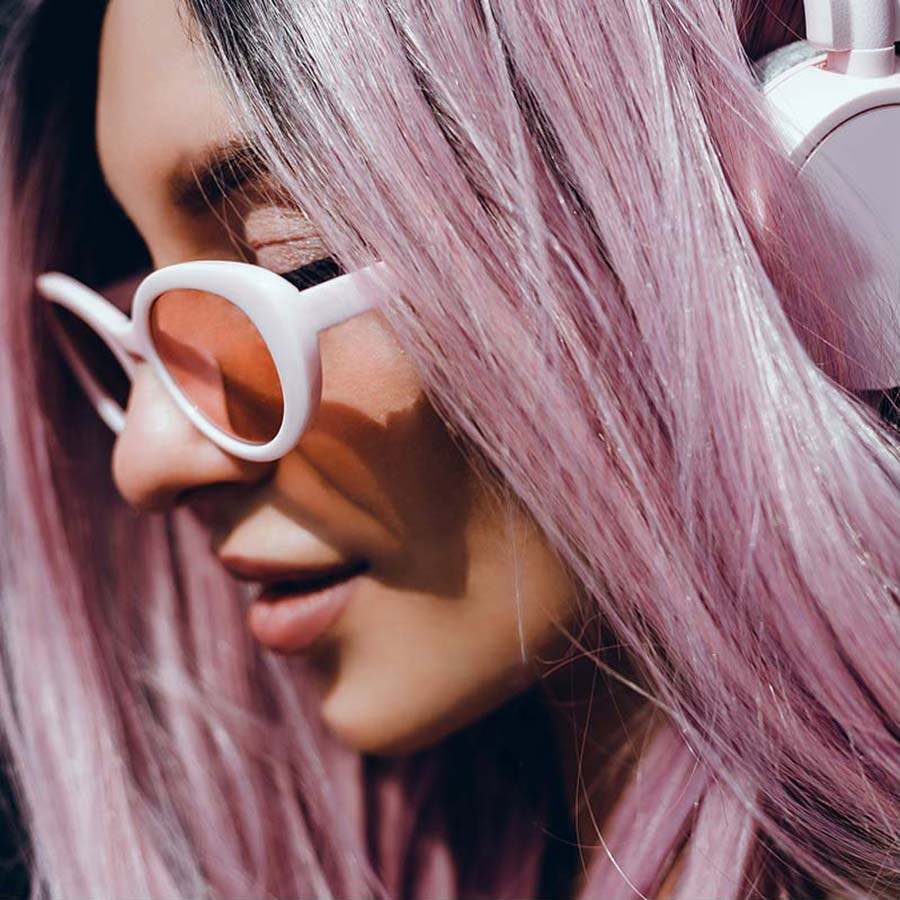 A woman with pink hair in white sunglasses