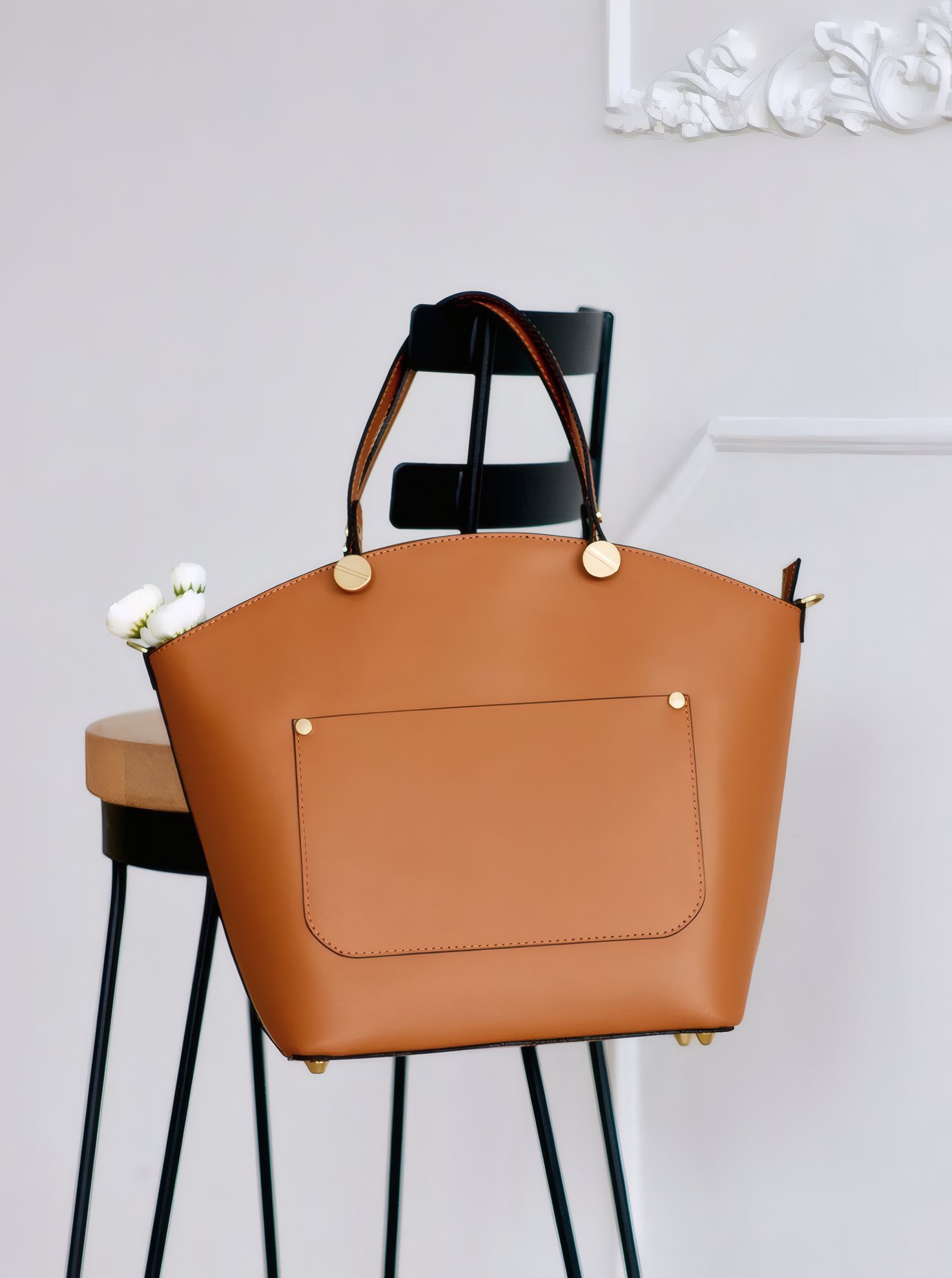 A cognac leather tote hanging from a bar stool