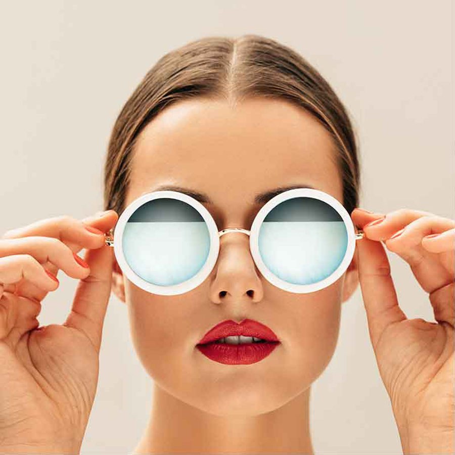 A woman holding white round sunglasses