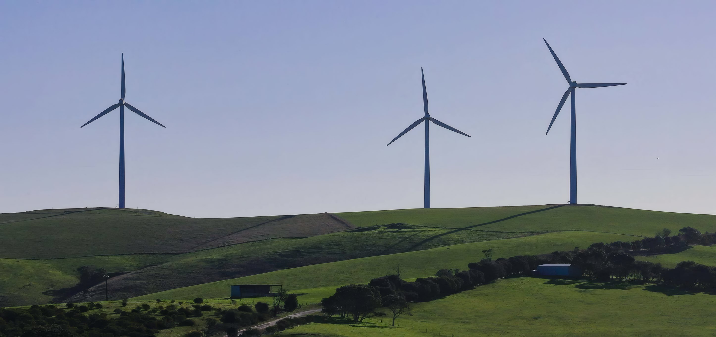 Three wind turbines over green hills