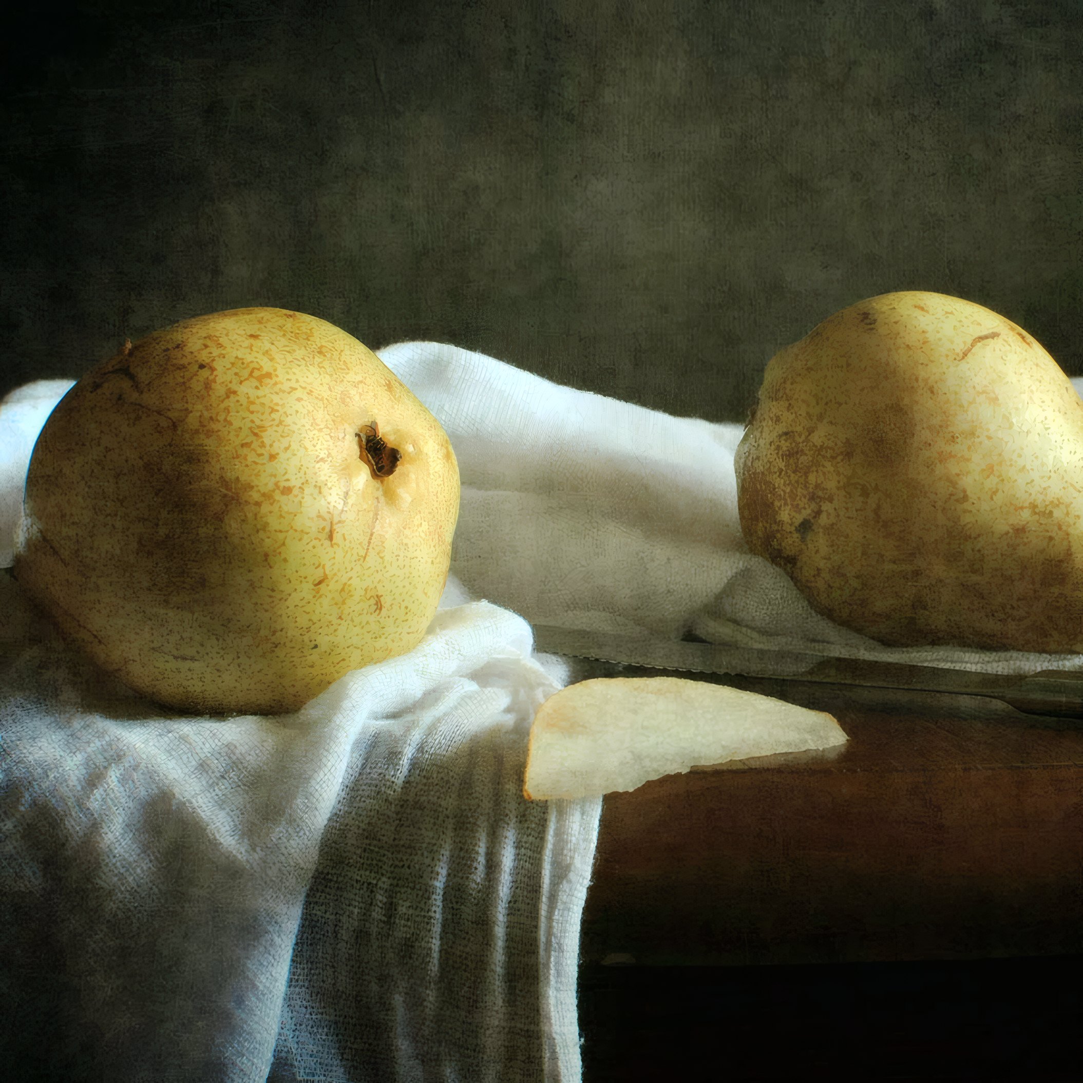 Two pears on white linen on a dark table