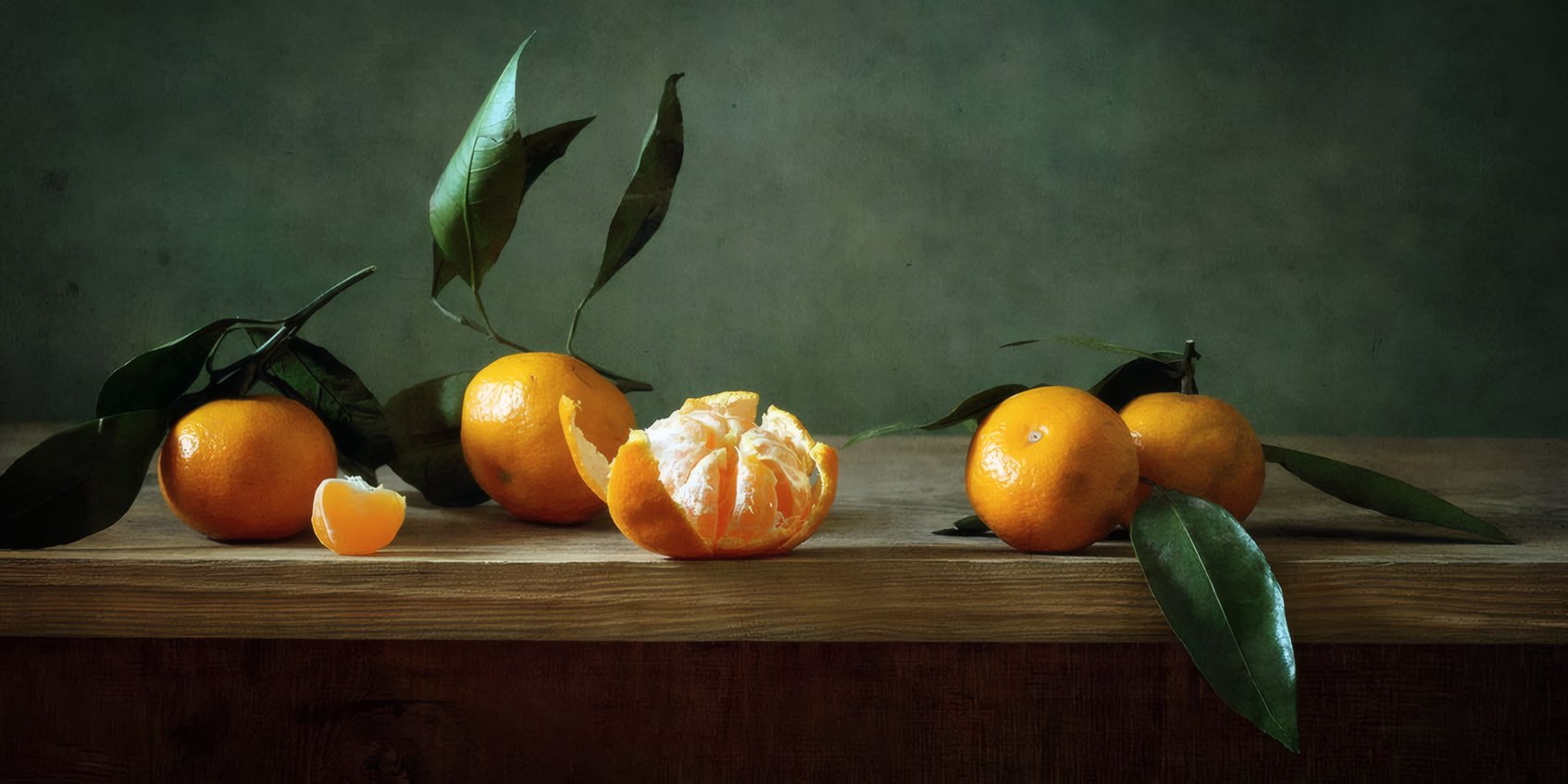 Tangerines with their leaves on a wooden ledge