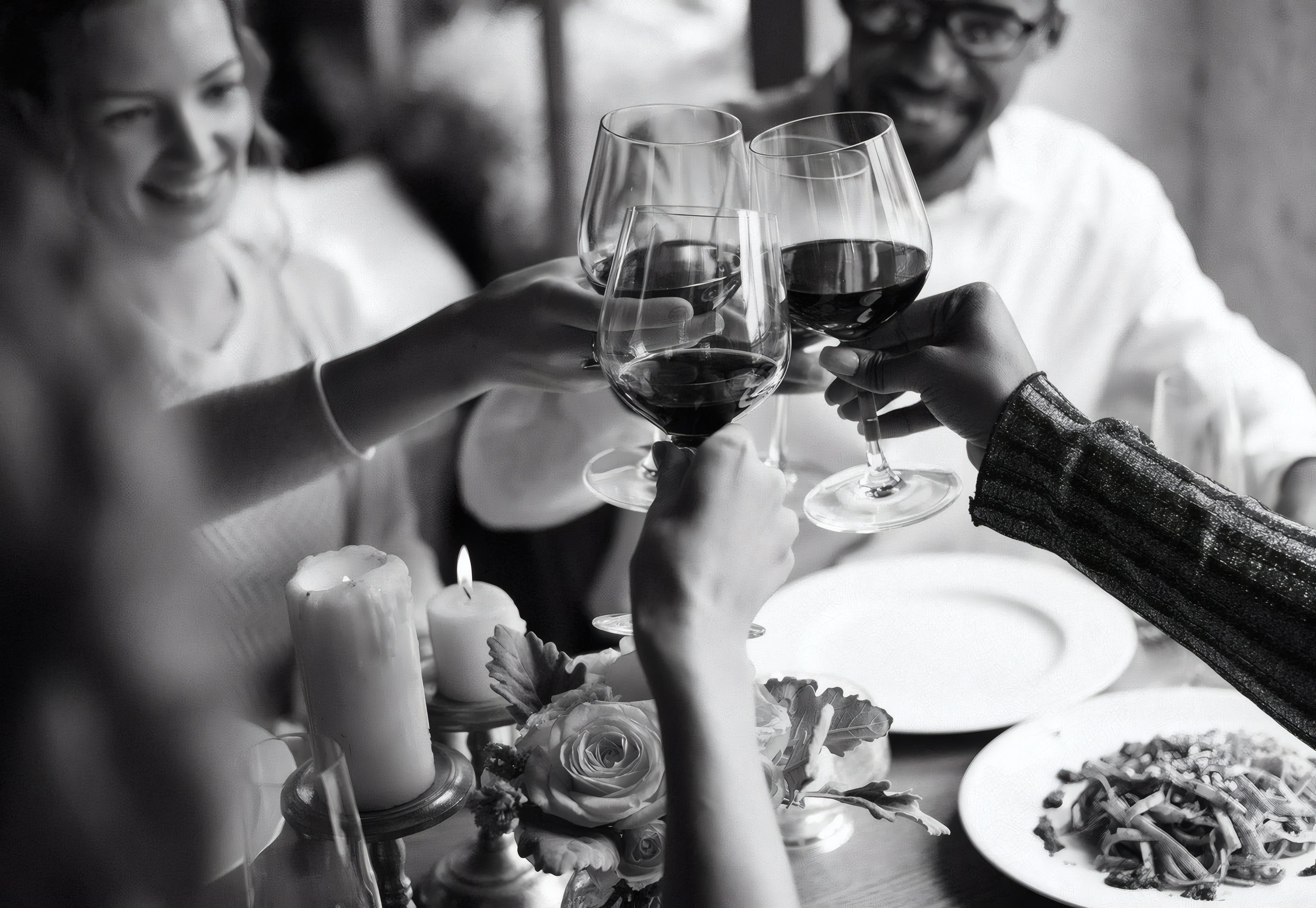 Friends raising glasses of red wine at dinner