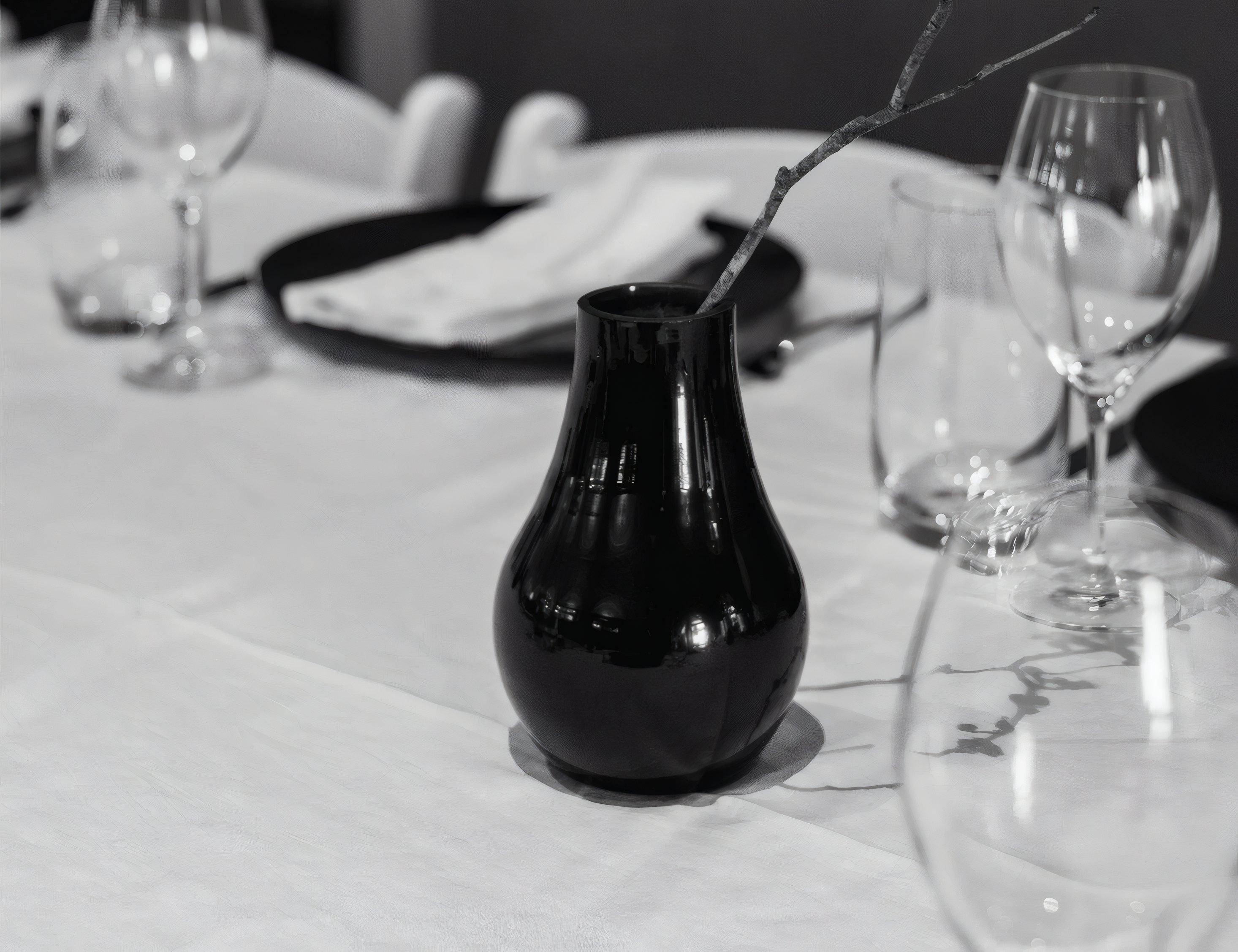 A laid bistro table with glasses and a black vase