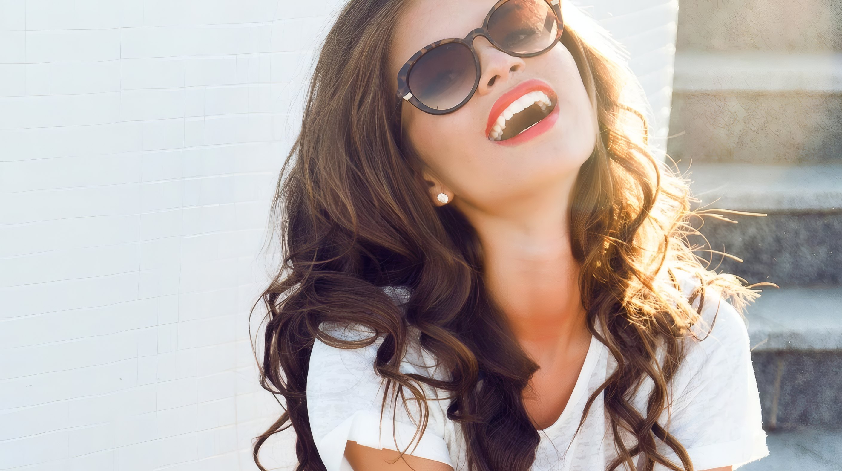 Mila laughing on the steps in round sunglasses