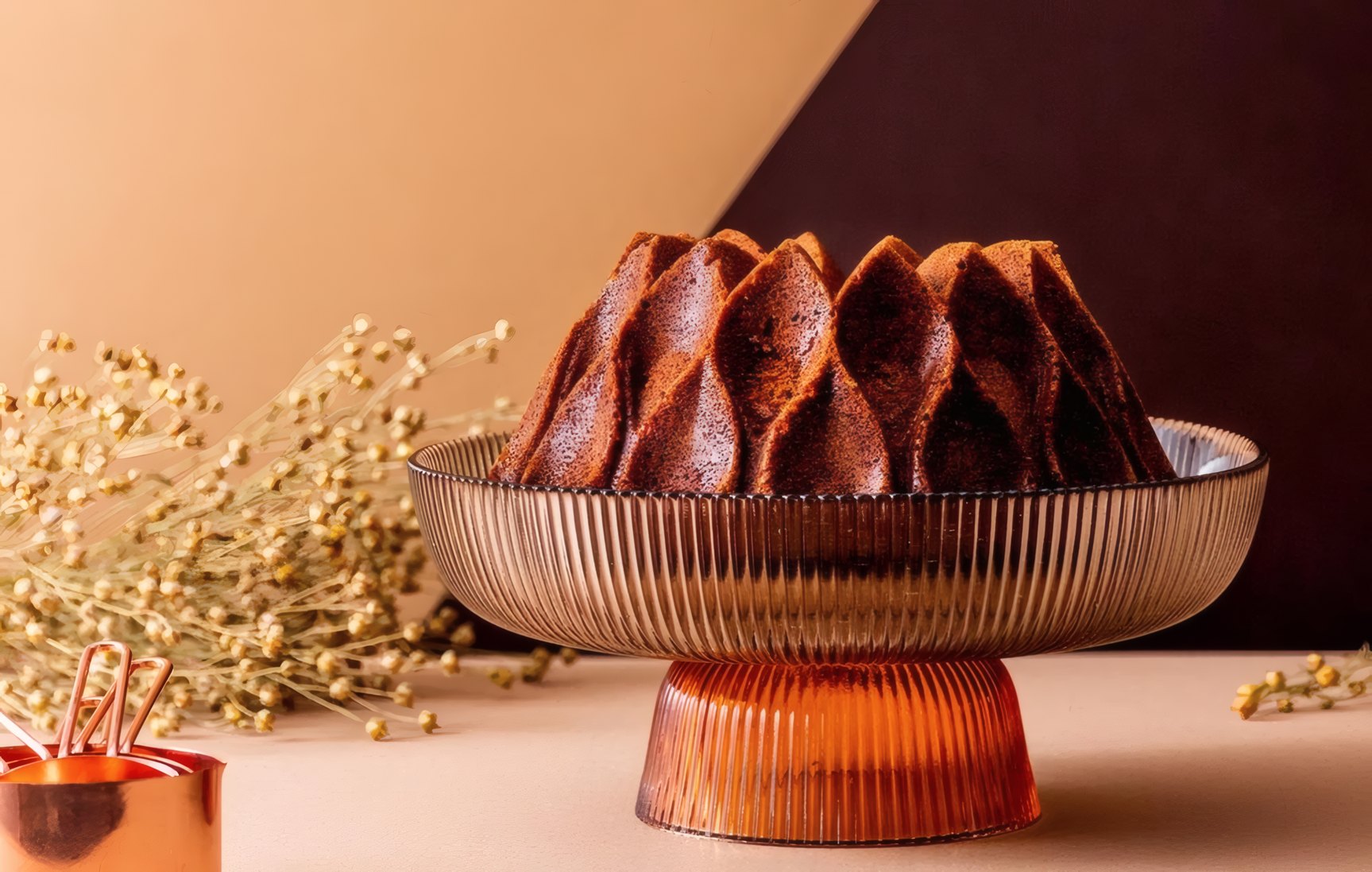 A chocolate crown cake on a fluted amber glass stand