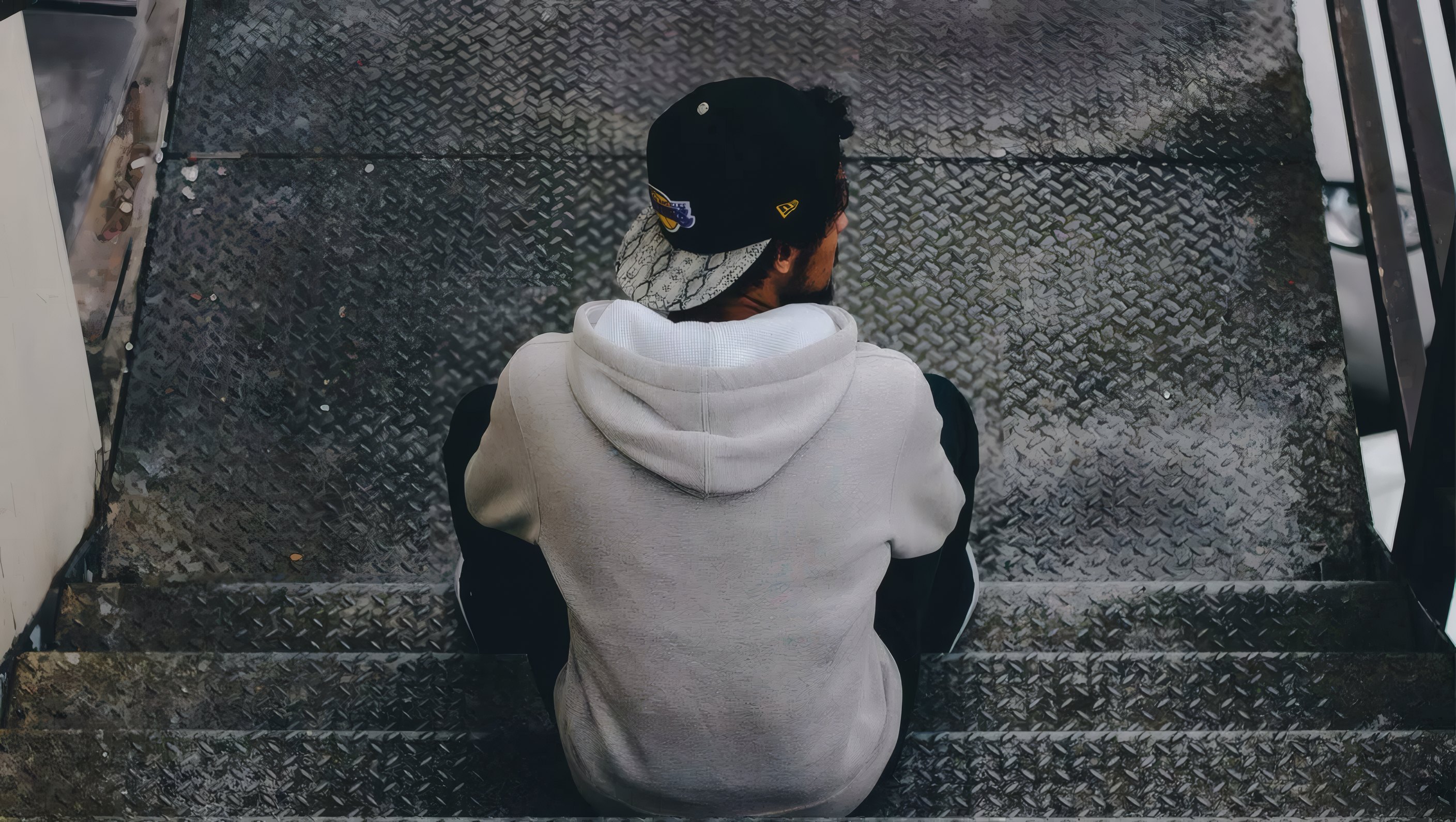 A grey hoodie seen from behind on a steel stair