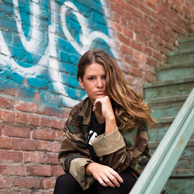 Nadia Reyes on the stairs by a graffiti wall
