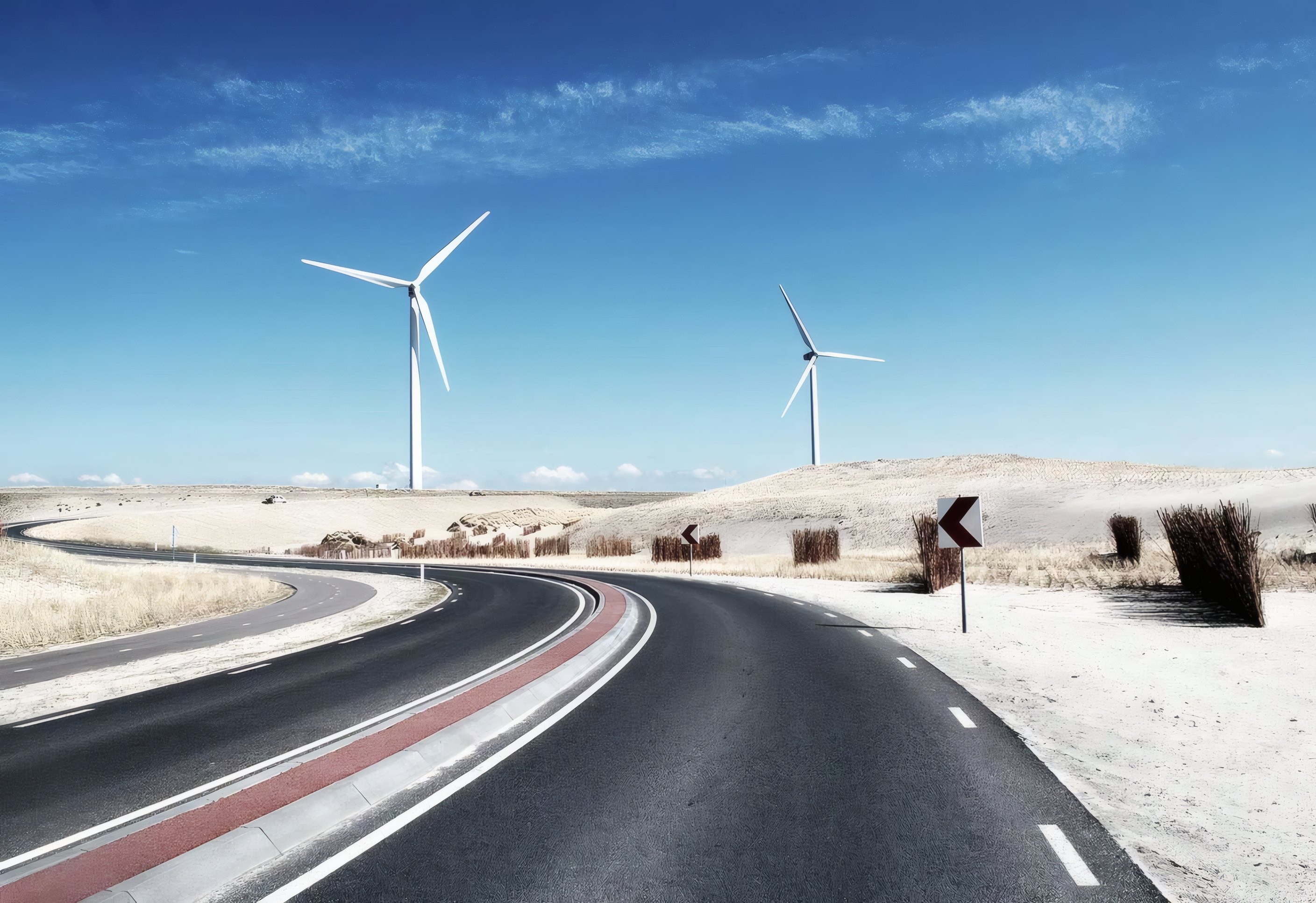 Wind turbines above a road through the hills