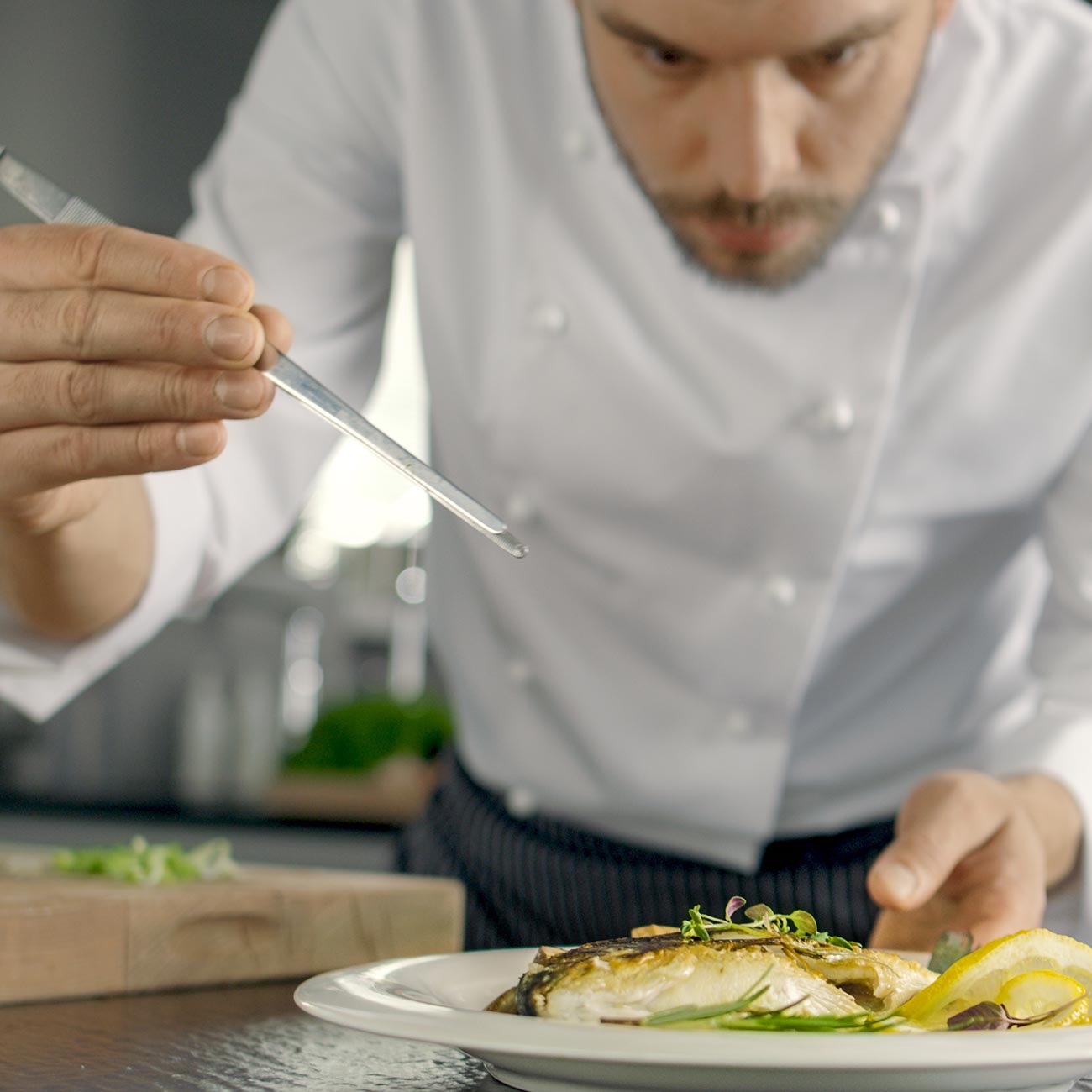 A chef plating fish at the pass