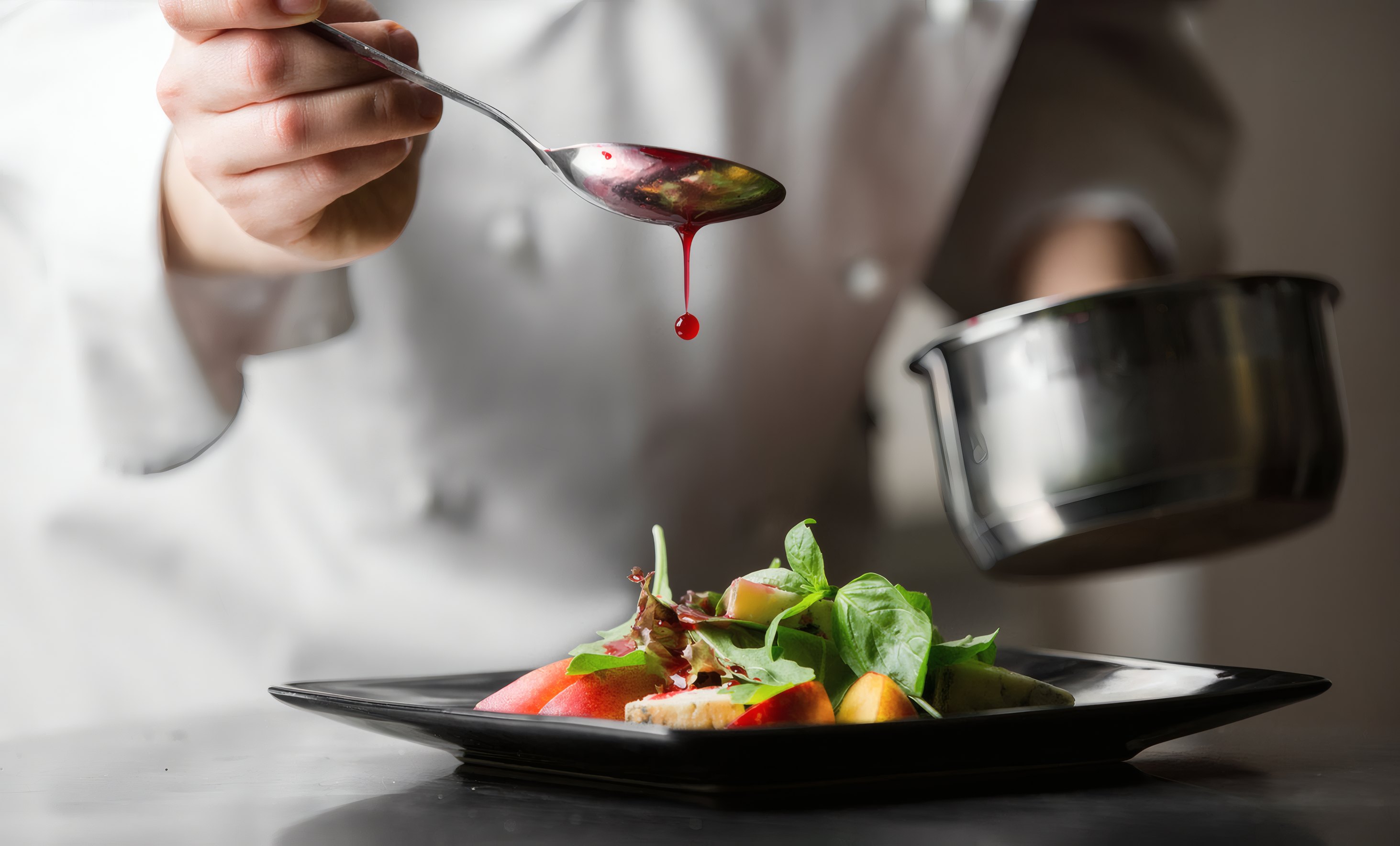 A chef spooning sauce onto a plated dish