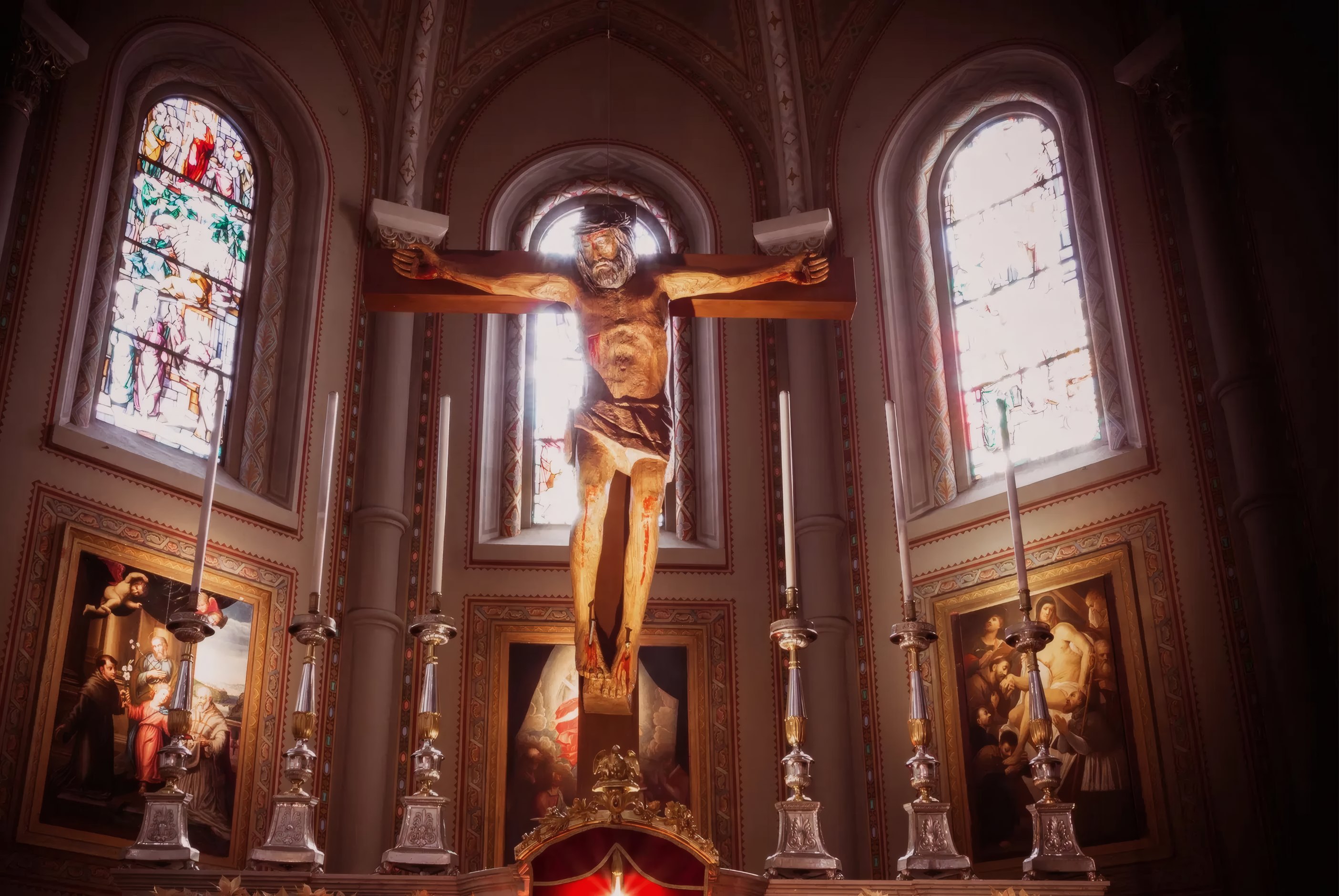 Crucifix above the altar of a candlelit cathedral