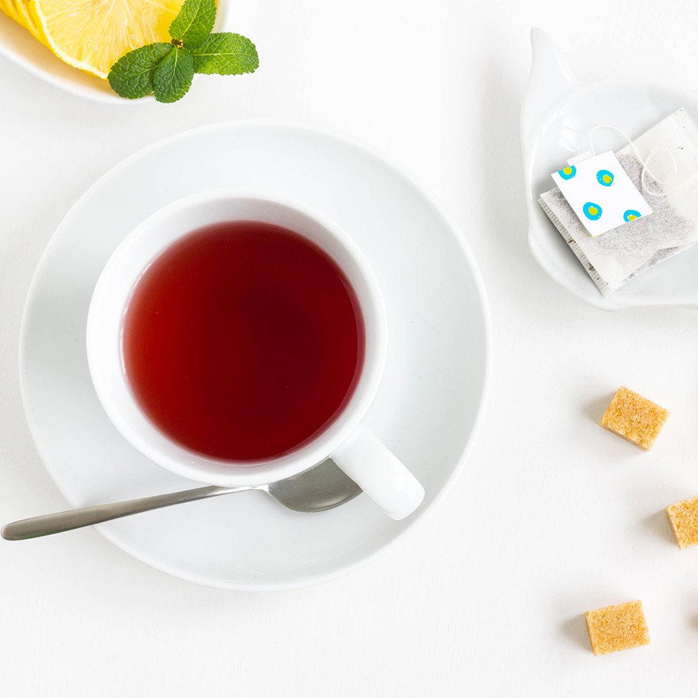 Red hibiscus tea in a white cup with brown sugar