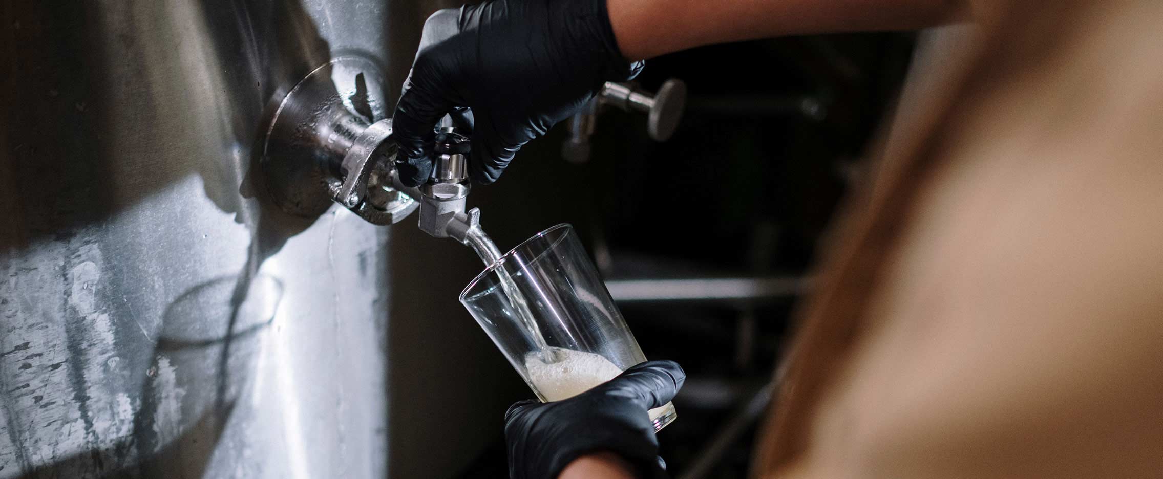 A brewer pours a fresh beer from the tank tap