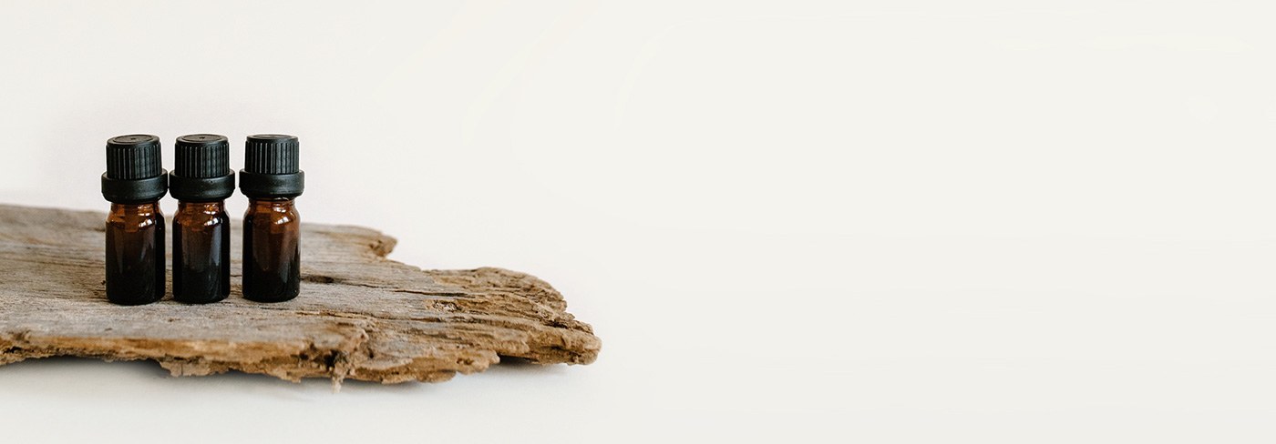 Three amber dropper bottles on a piece of driftwood