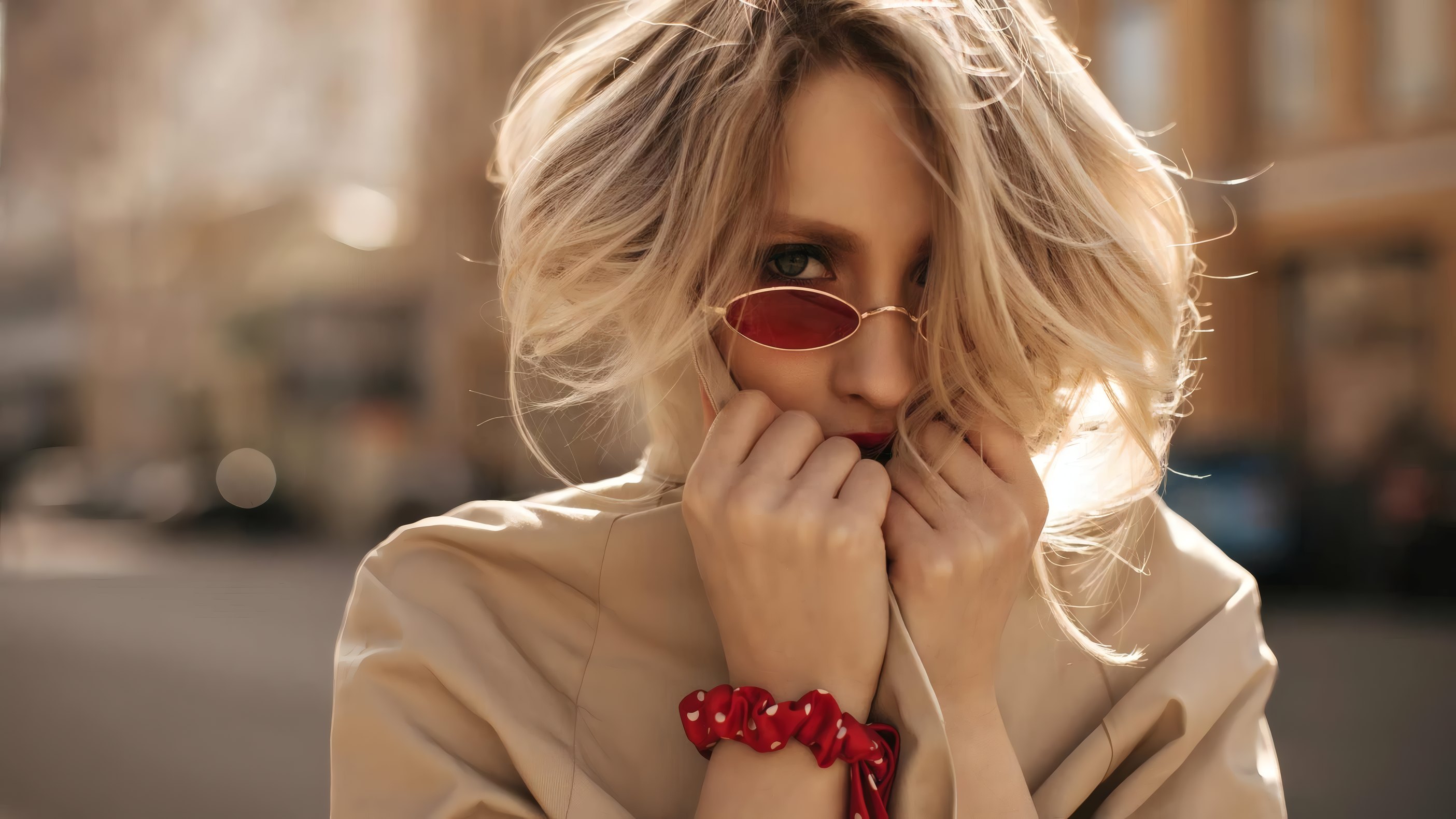 A woman in red sunglasses and a camel coat