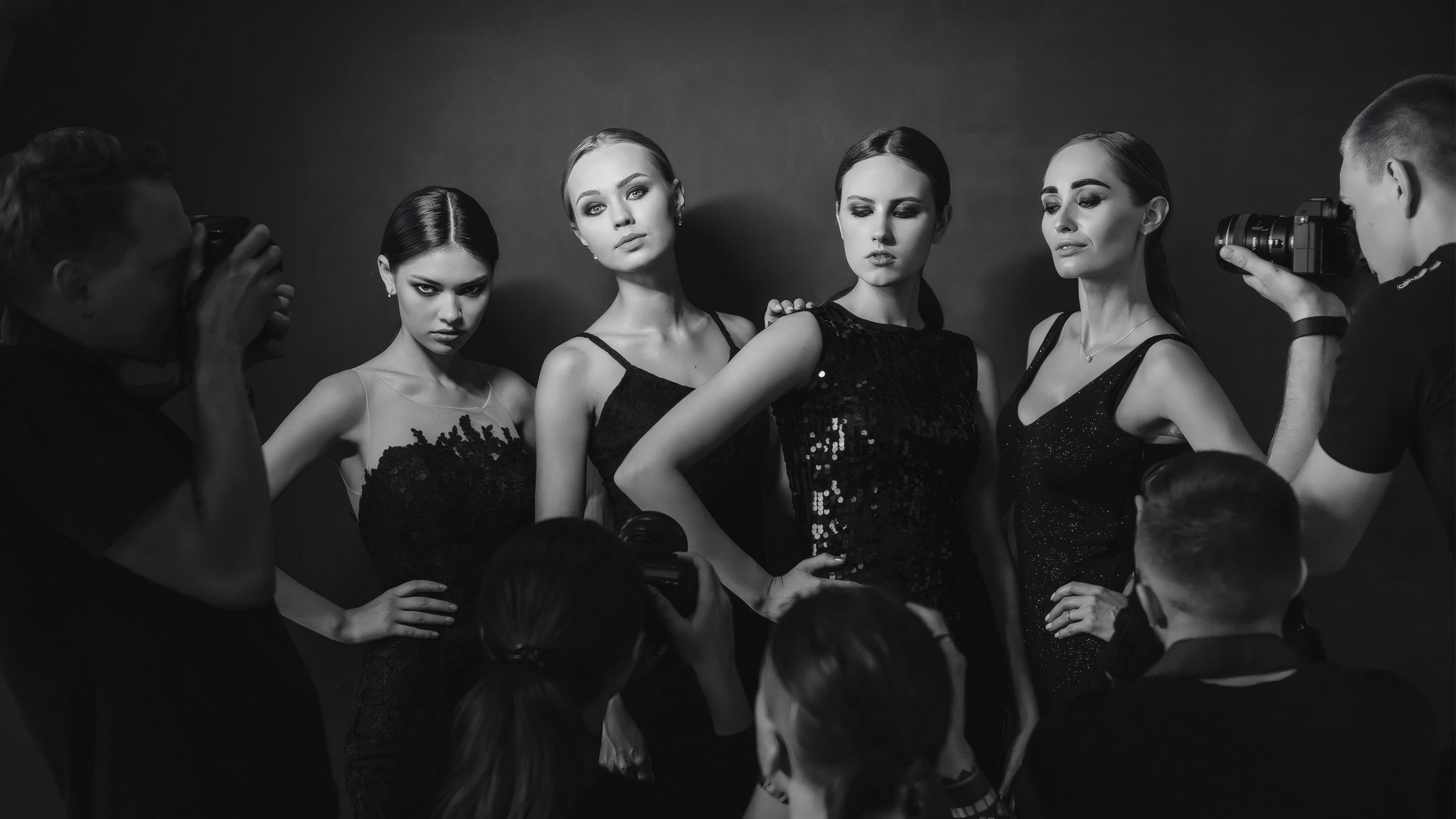 Five models in black being photographed backstage