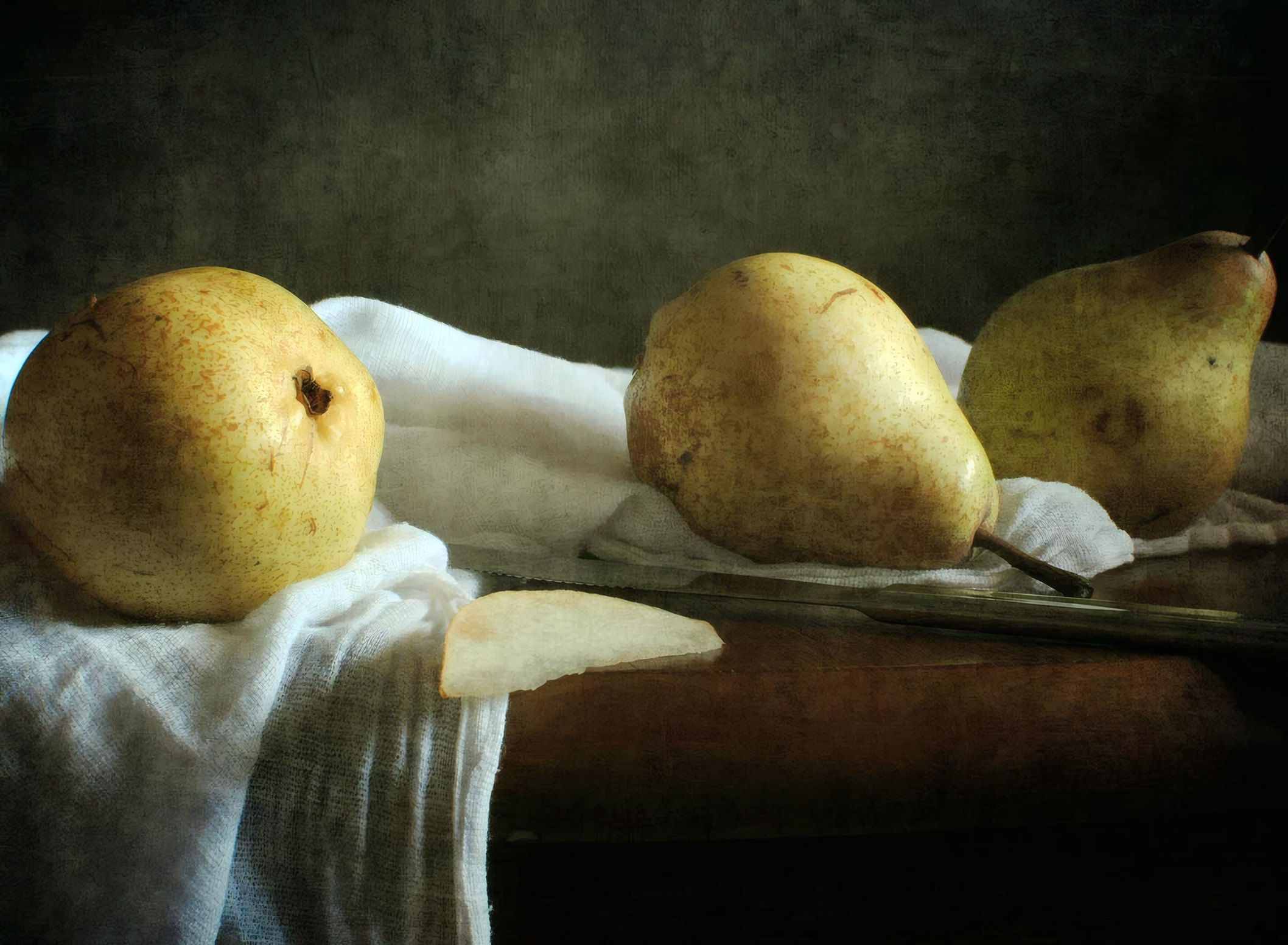 Two pears on white linen on a dark walnut table