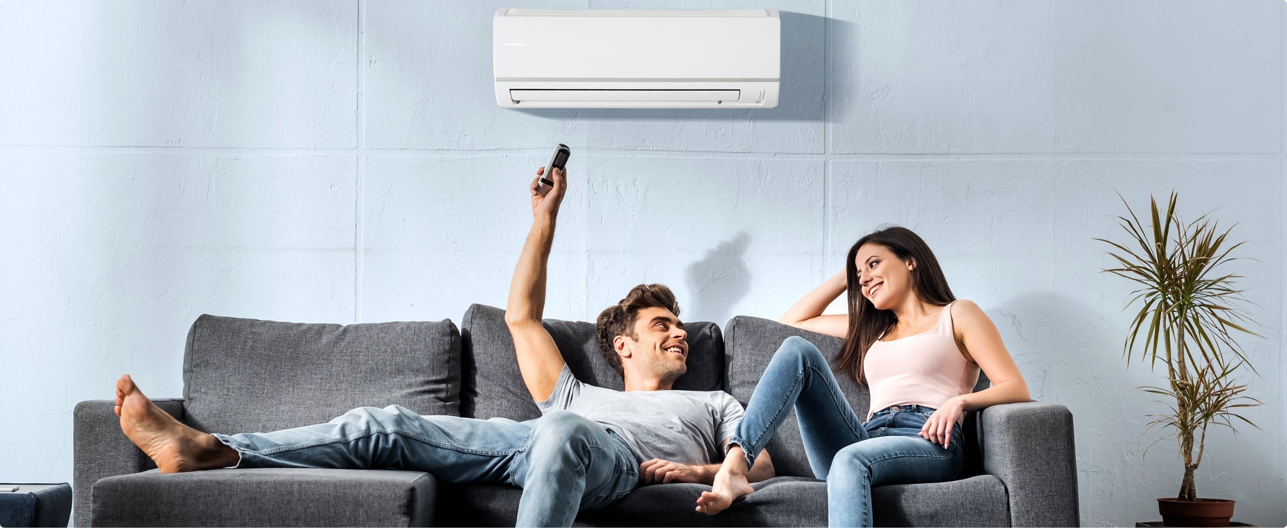 A couple resting on a sofa under a cooling air conditioner