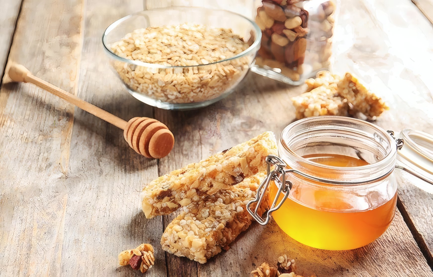 An open jar of honey with comb and oats on a wooden table