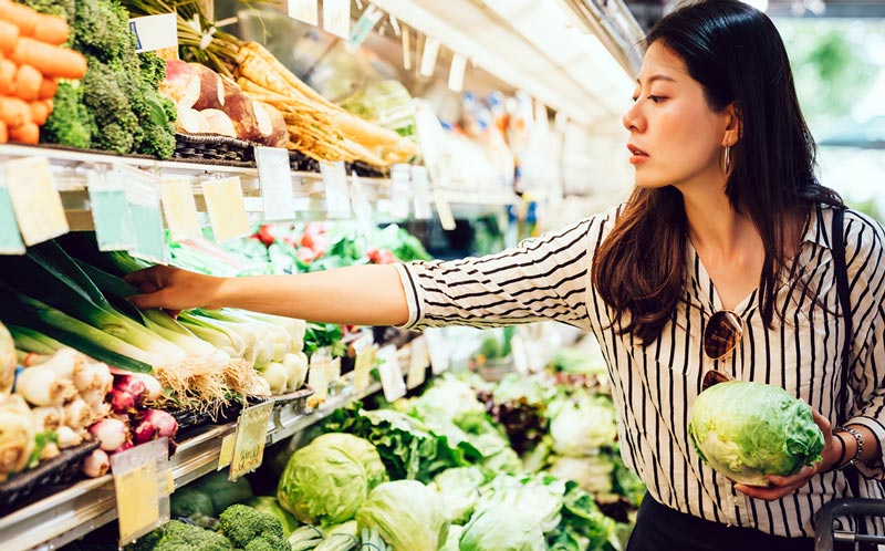 A shopper choosing produce at a market stall
