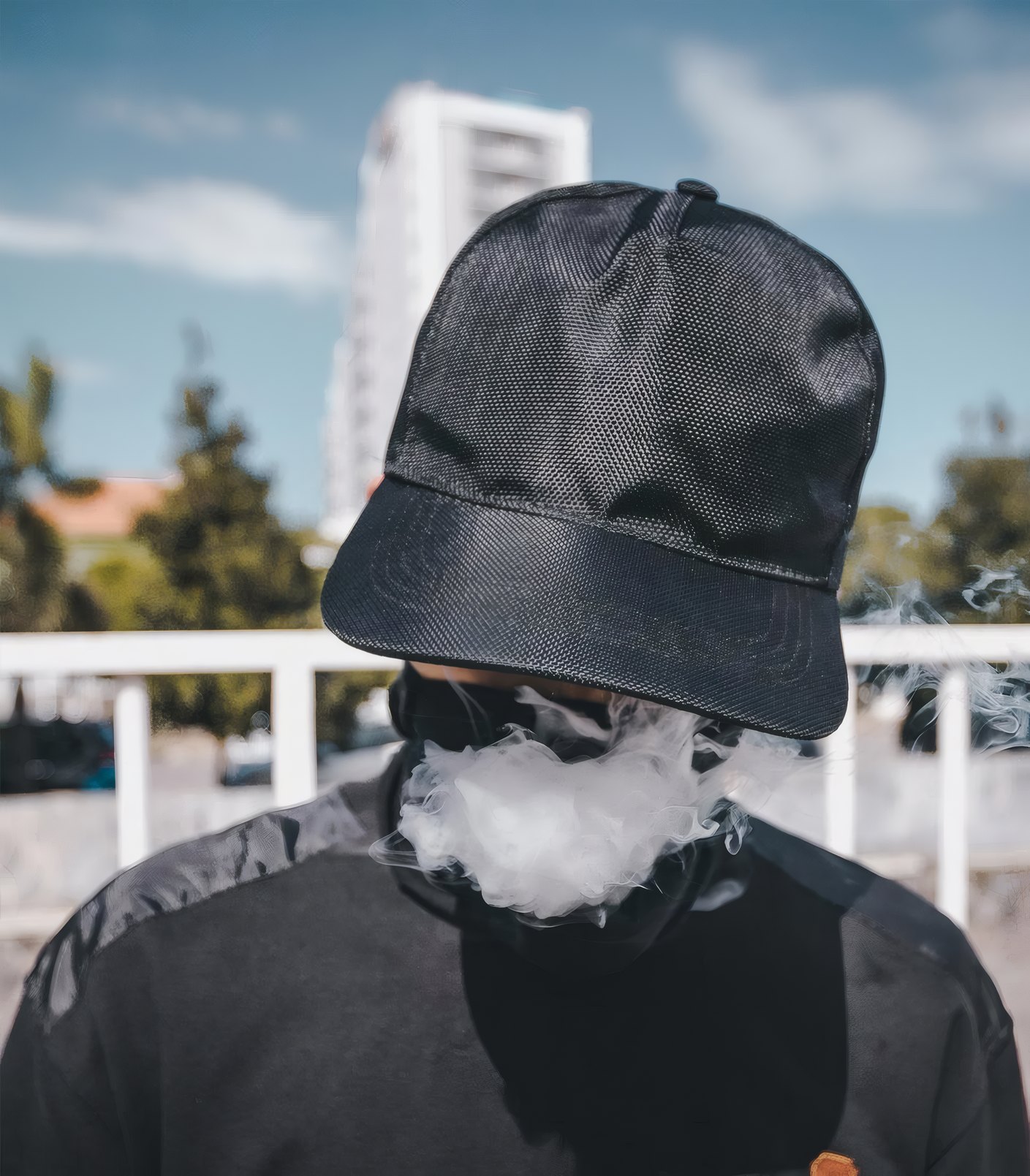 A man in a black cap breathing out smoke