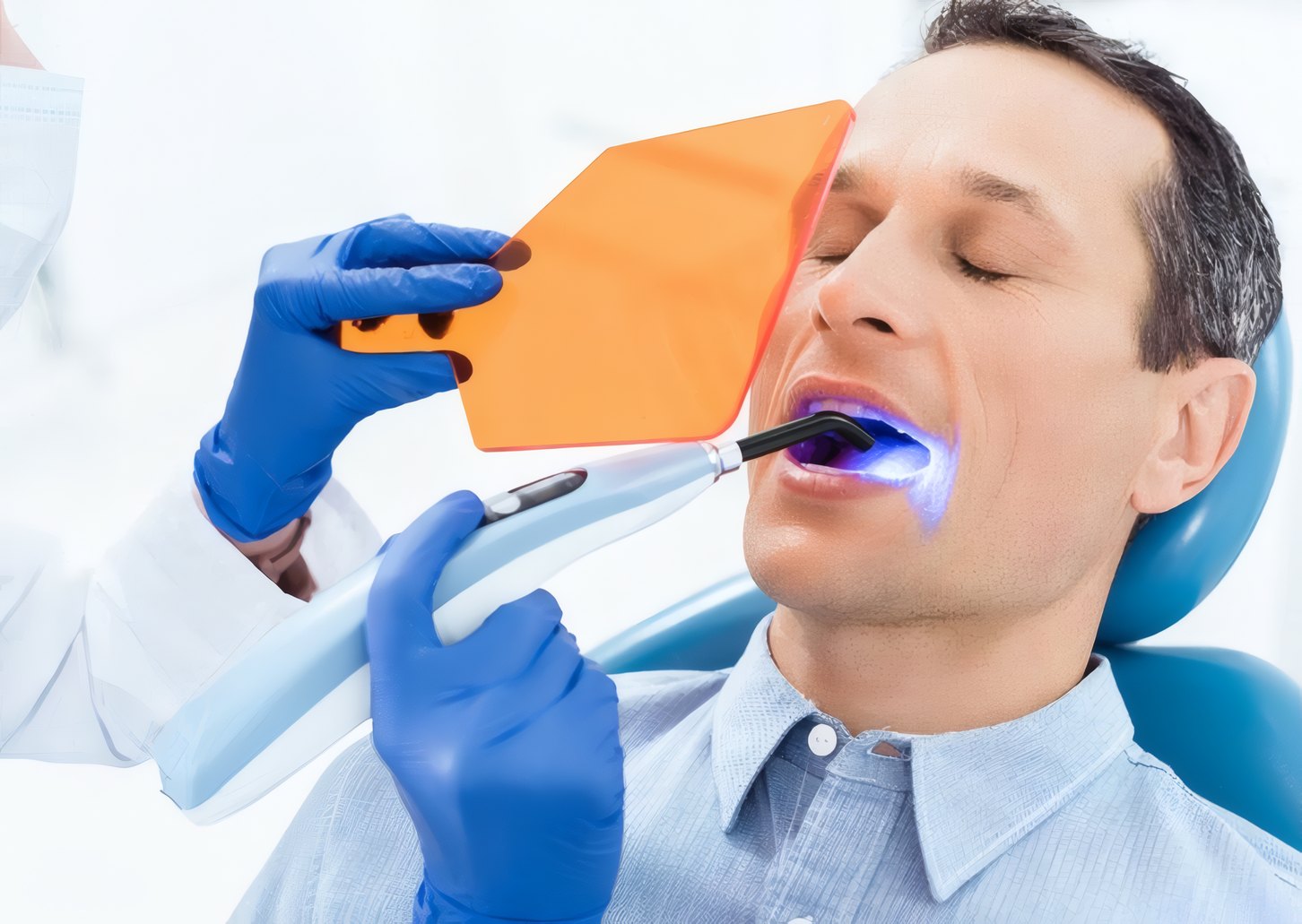 A patient in the dental chair during a curing light treatment