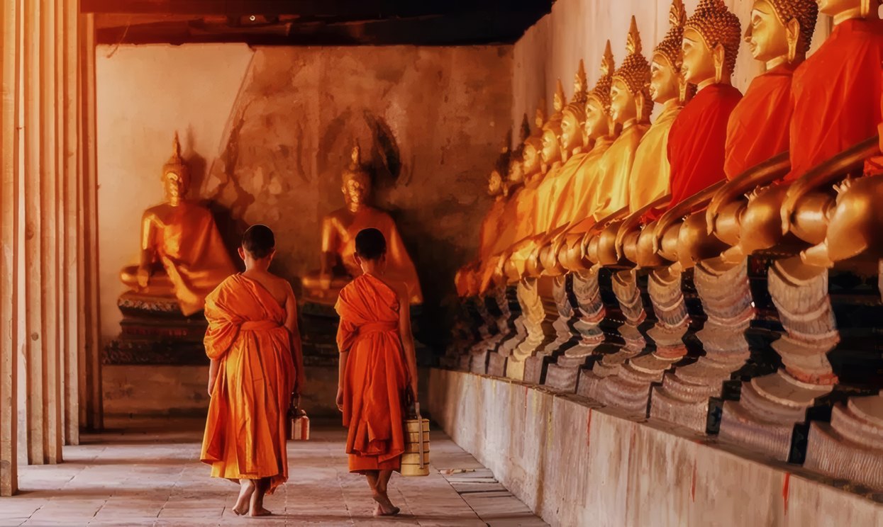 Monks walking between rows of golden Buddhas