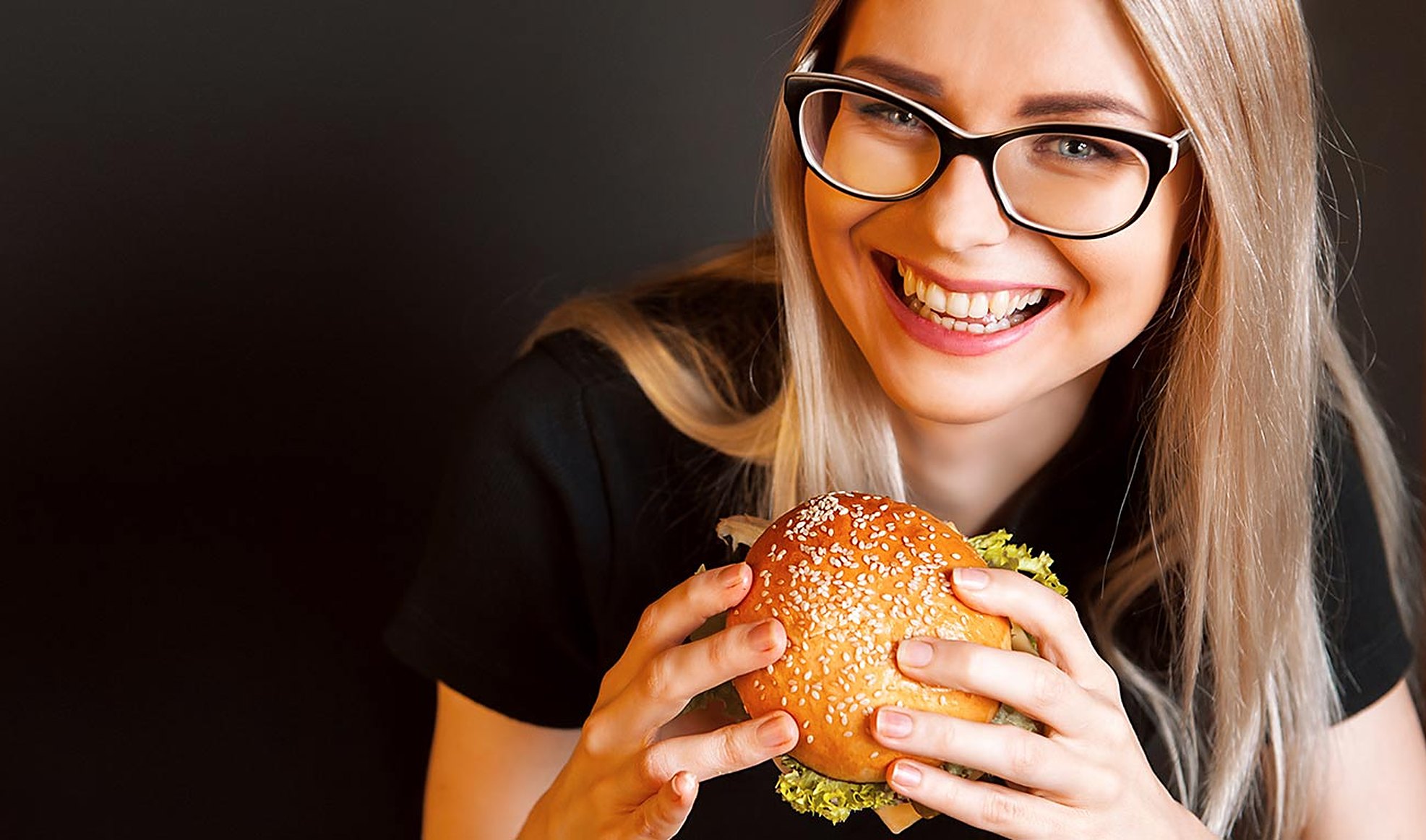 A smiling guest holding a big burger with both hands